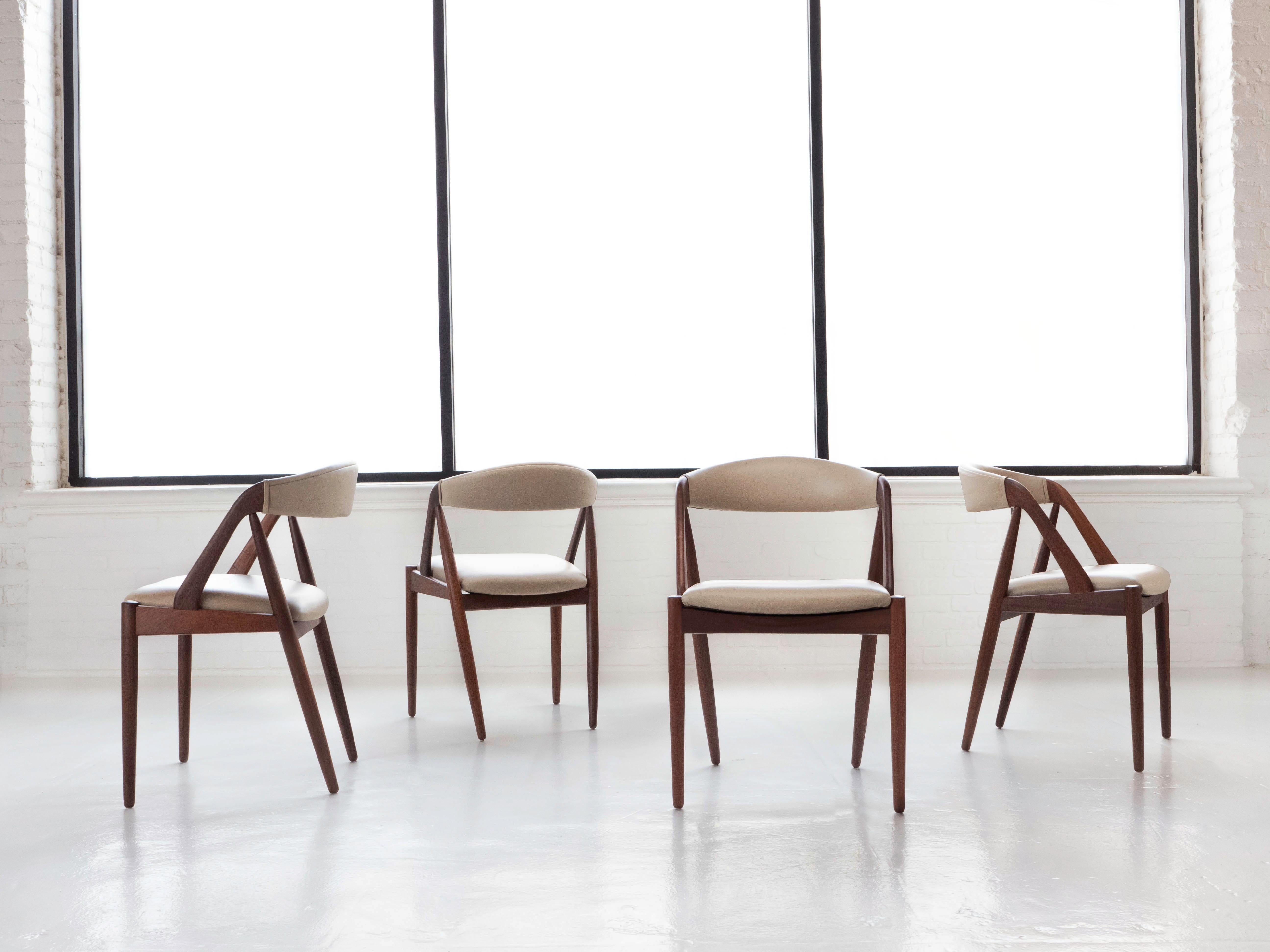A set of 4 dining chairs by Danish designer Kai Kristiansen, Schou Andersen circa 1960’s. Known as his Model 31 dining chairs, these sculpted chairs each boast a solid teak frame, sleek lines, tapered legs, and a curved back support. 

The chairs