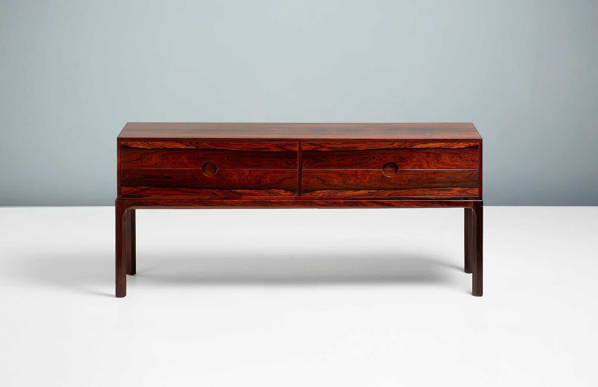 Kai Kristiansen.

Model 384 chest, c1960.

Low, 4-drawer chest made from highly figured rosewood, produced by Aksel Kjersgaard in Odder, Denmark, c1960. Features Kristiansen’s trademark circular drawer pulls. 

Measures: H 52 cm 
W 118 cm 
D