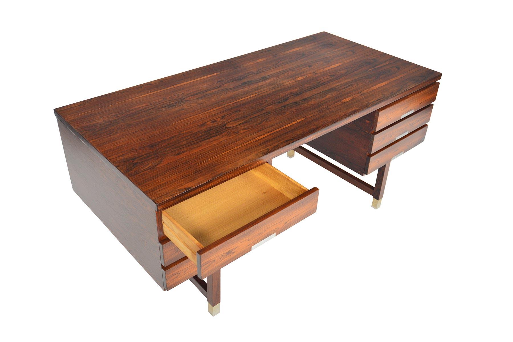 This Danish modern executive desk model EP 401 in Brazilian rosewood was designed by Kai Kristiansen for Feldballes Møbelfabrik in the 1960s. The kneehole is nestled between two banks of drawers with flush brushed aluminum pulls. The back side of