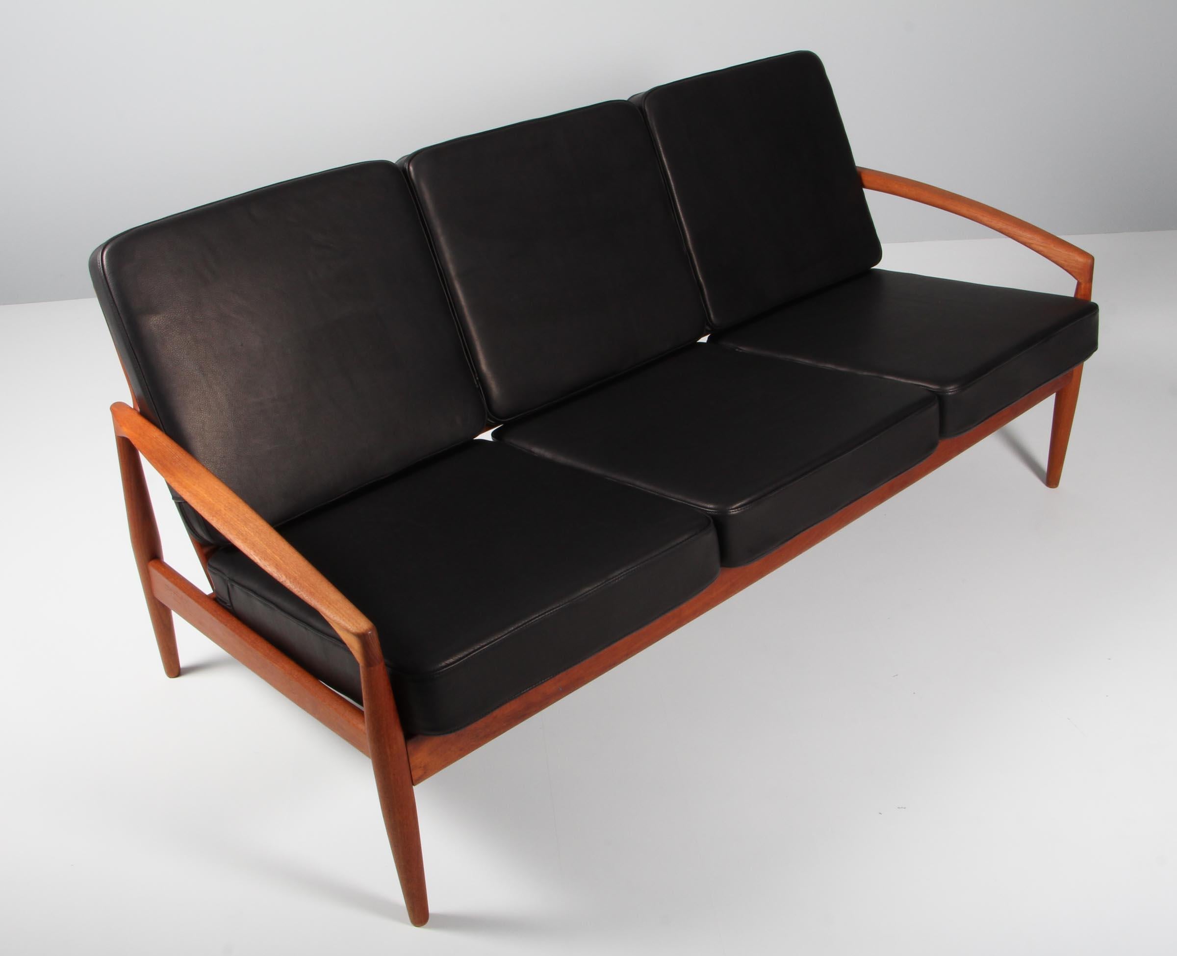 Kai Kristiansen three-seat sofa with frame of teak and organic armrests.

New upholstered with black aniline leather from Arne Sørensen.

Model paperknife, made by Magnus Olsen.