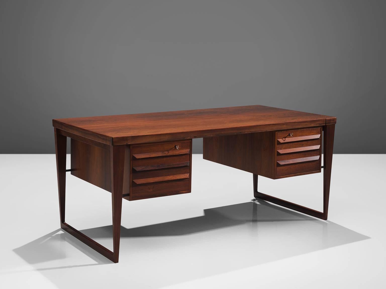 Kai Kristiansen for Feldballes Møbelfabrik, desk model 70, rosewood, Denmark, design 1958, production 1960s.

This sculptural freestanding desk is executed with two solid rosewood sled bases and contains three drawers on both sides which can be