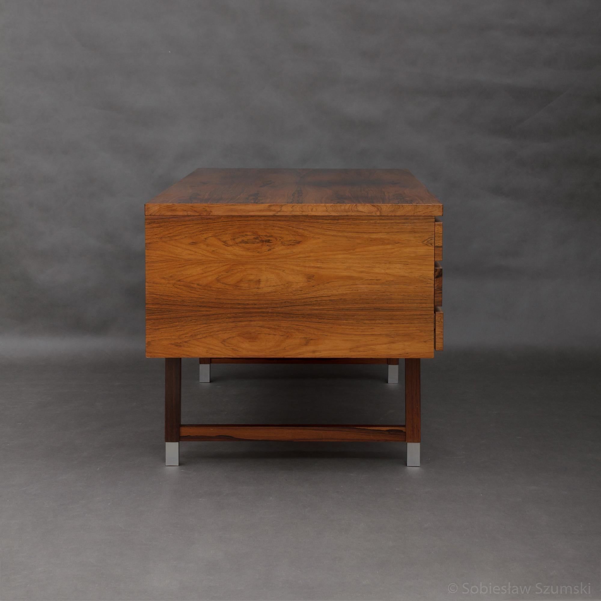 Freestanding desk designed by Kai Kristiansen in the 1960s and manufactured by Feldballes Møbelfabrik. It features six deep drawers in the front and shelves on the back of the piece. The entire piece is in rich grain rosewood with aluminium handles