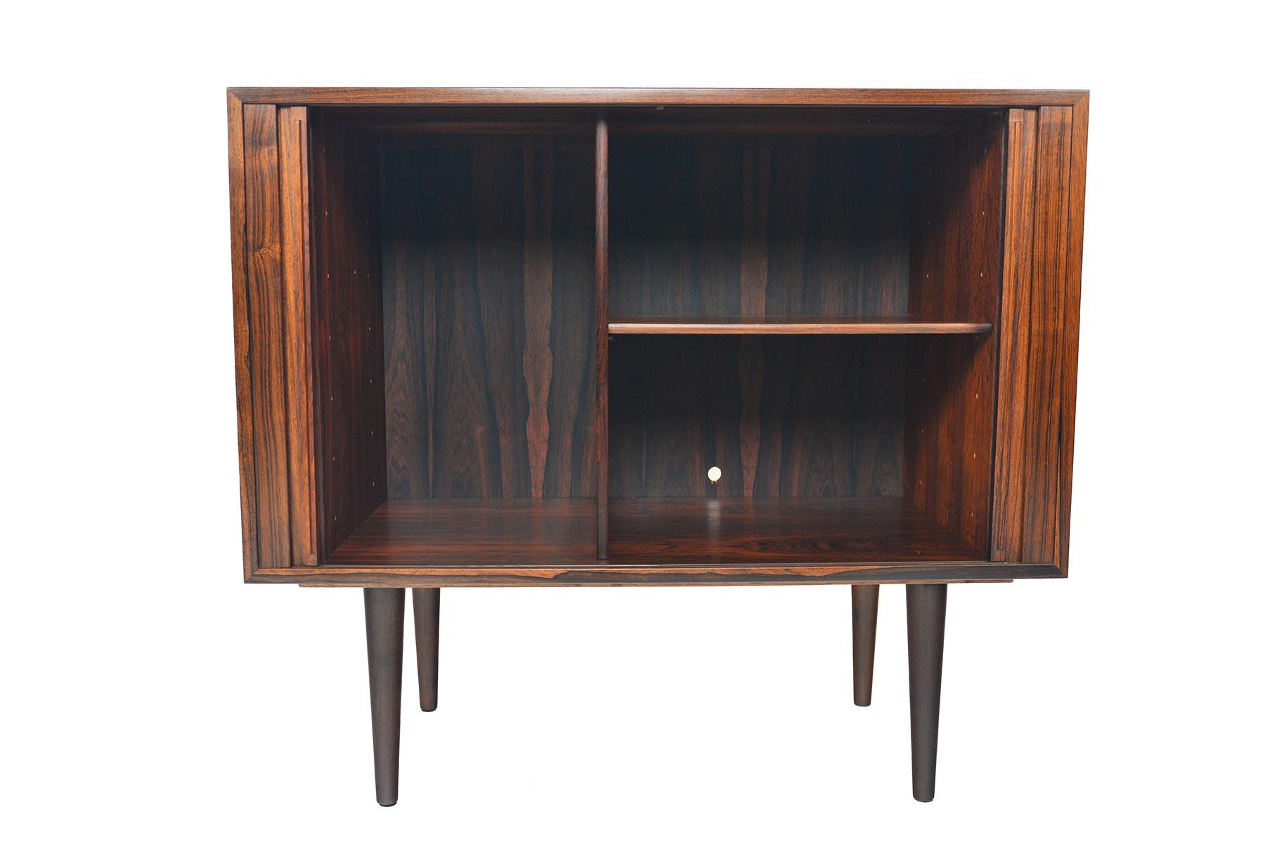 This Danish modern midcentury small tambour door credenza in rosewood was designed by Kai Kristiansen in the 1960s. This fantastic piece features two tambour doors which open to reveal two bays with an adjustable. In excellent original condition