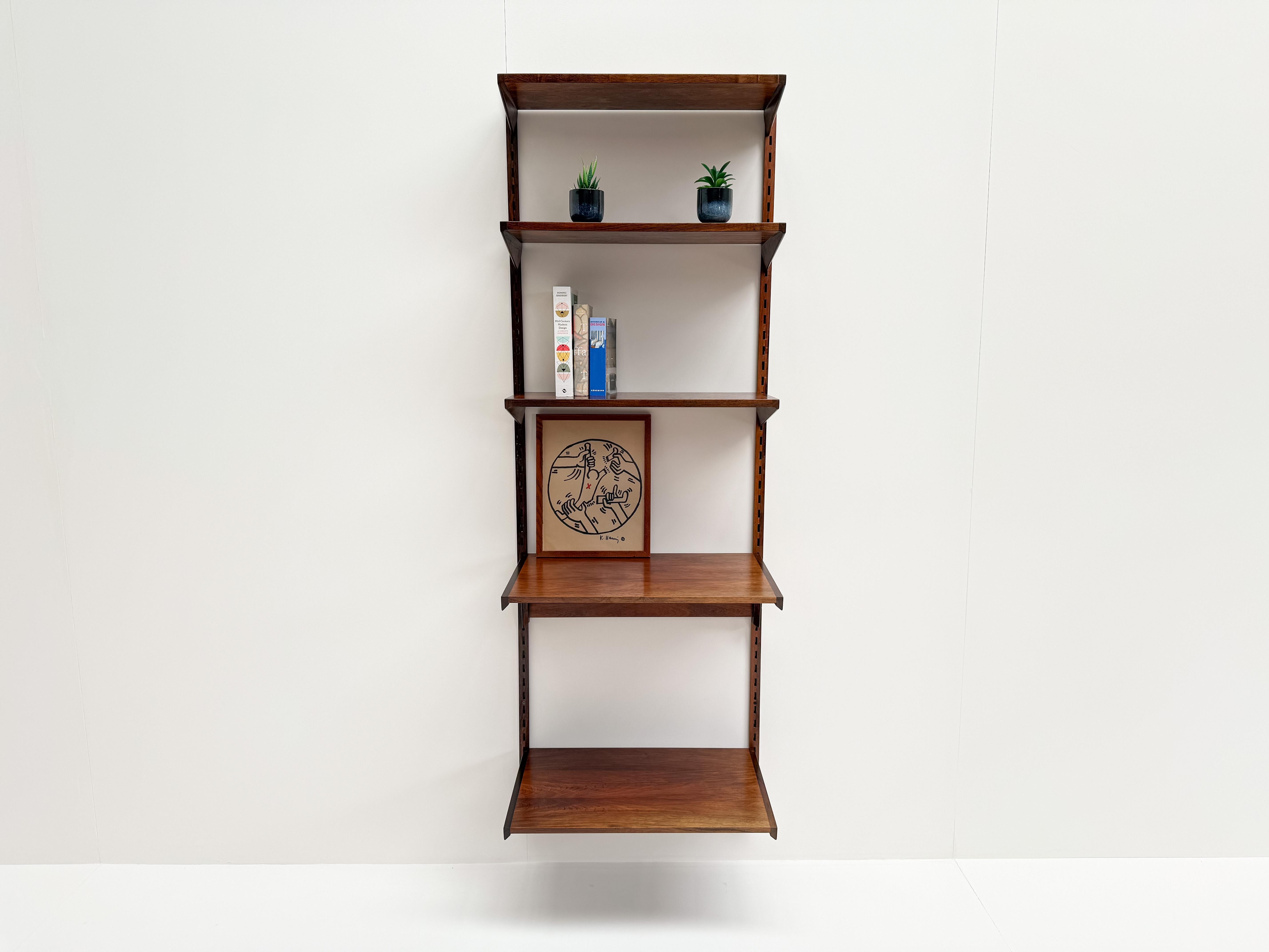Un pezzo senza tempo del design scandinavo: questa elegante scaffalatura a muro è stata disegnata da Kai Kristiansen negli anni '60 e realizzata in ricco legno di palissandro. Con la sua forma minimalista e le calde venature del legno, incarna le