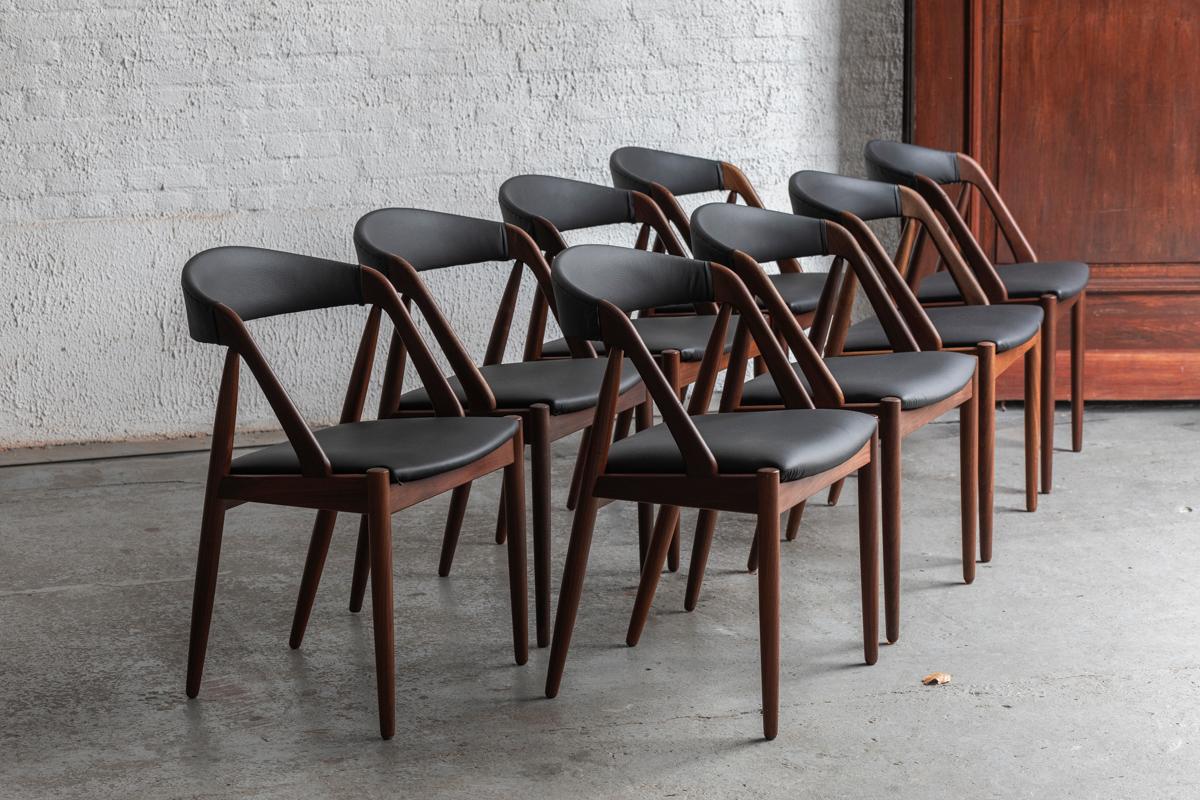 Set of 8 dining chairs ‘Model 31’, designed by Kai Kristiansen and produced in Denmark in the 1960’s. The frames in solid dark rosewood were re-upholstered by the previous owner in a black faux leather. Some small using marks as shown in the