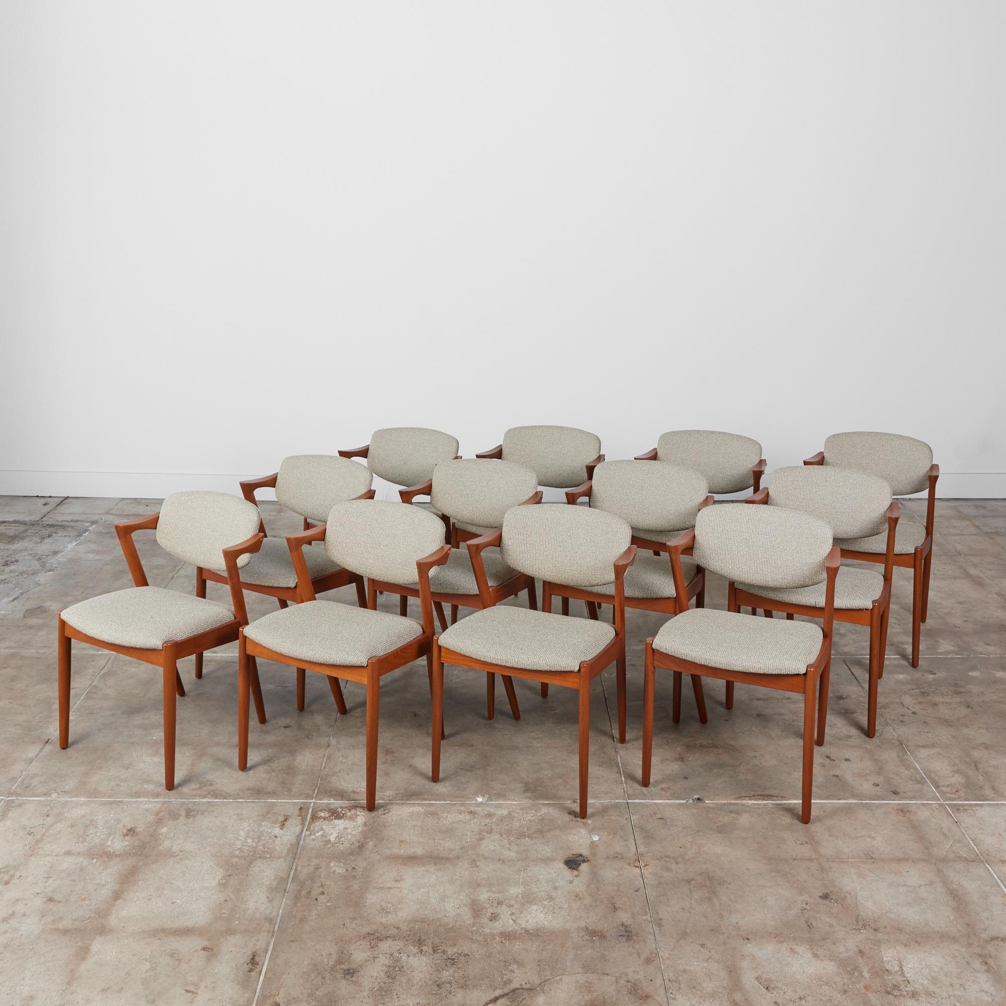 Set of twelve Danish modern teak dining chairs by Kai Kristiansen for Schou Andersen, with a sculpted frame and sharp lines. The model 42 chair was the first chair with armrests supported by the rear legs of the frame, and was a critical darling