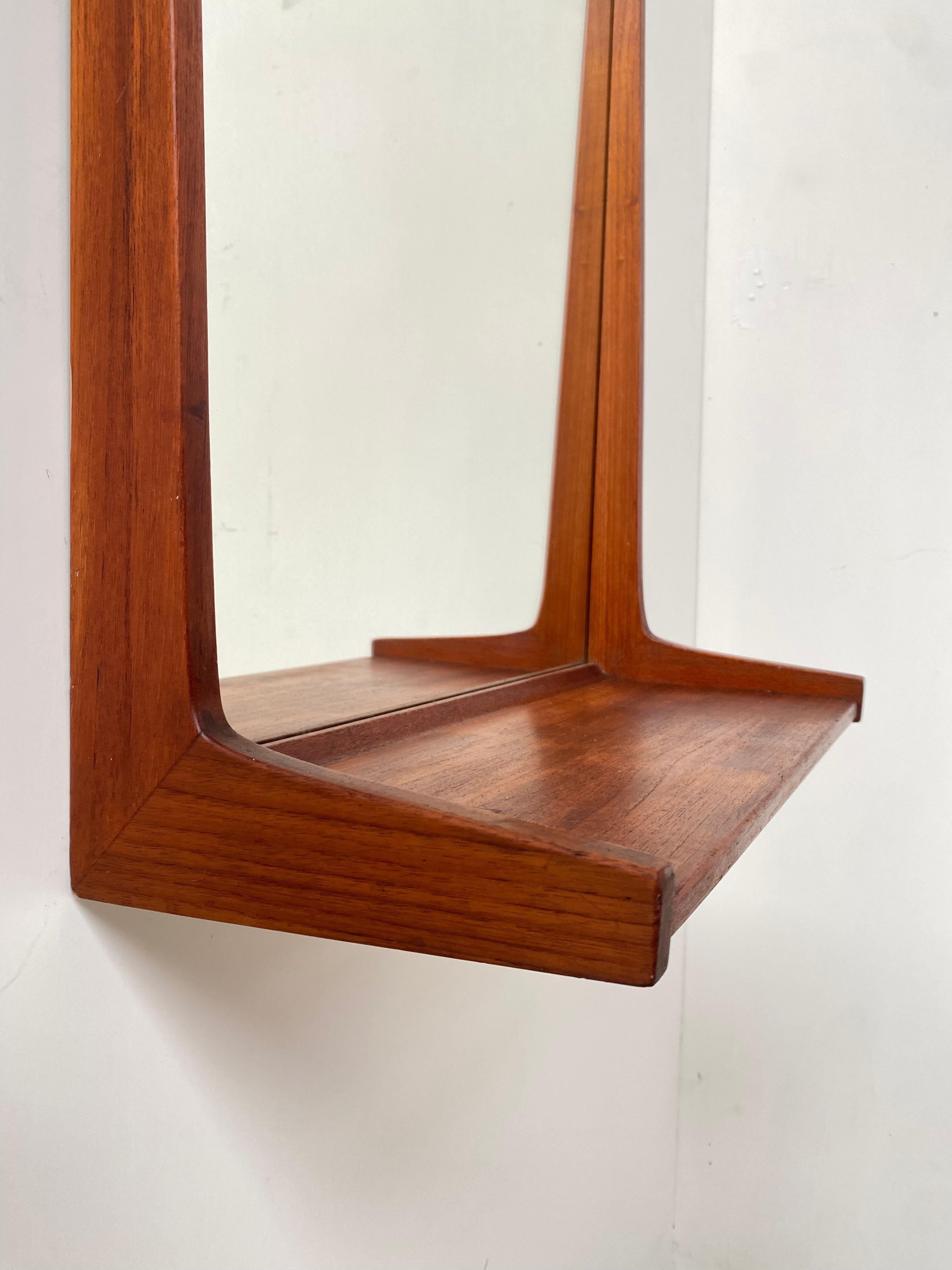 Miroir en teck massif avec étagère conçu par Kai Kristiansen pour Aksel Kjersgaard, fabriqué dans les années 1960.

La forme minimaliste représente un grand exemple de design moderne danois du milieu du siècle dernier.

Estampillé au dos avec le
