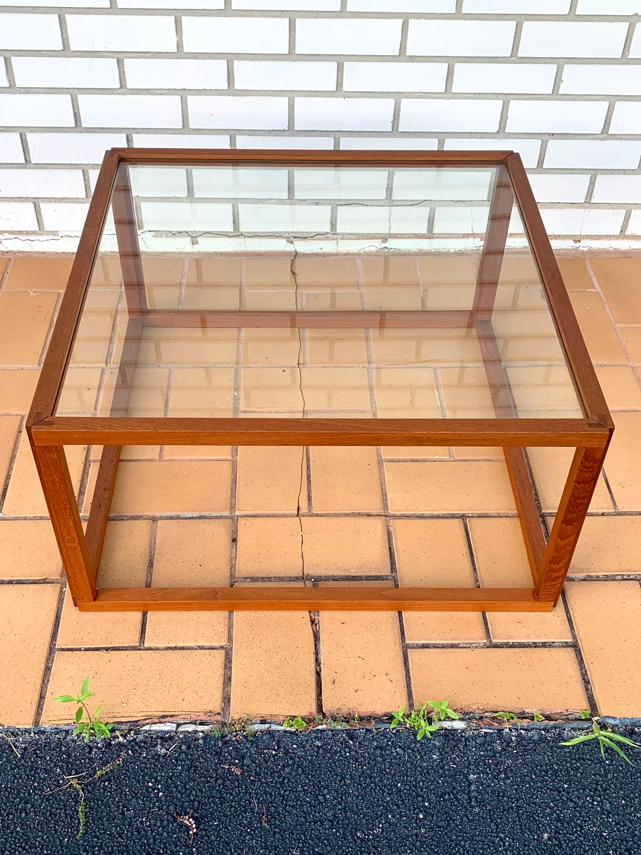 Mid-Century Modern coffee table by Kai Kristiansen. Made from solid teak wood and glass. Refinished. Gorgeous minimalist design offering a sleek and elegant profile. Simple and organic form. Frame is cut so the glass fits perfectly inside the frame.