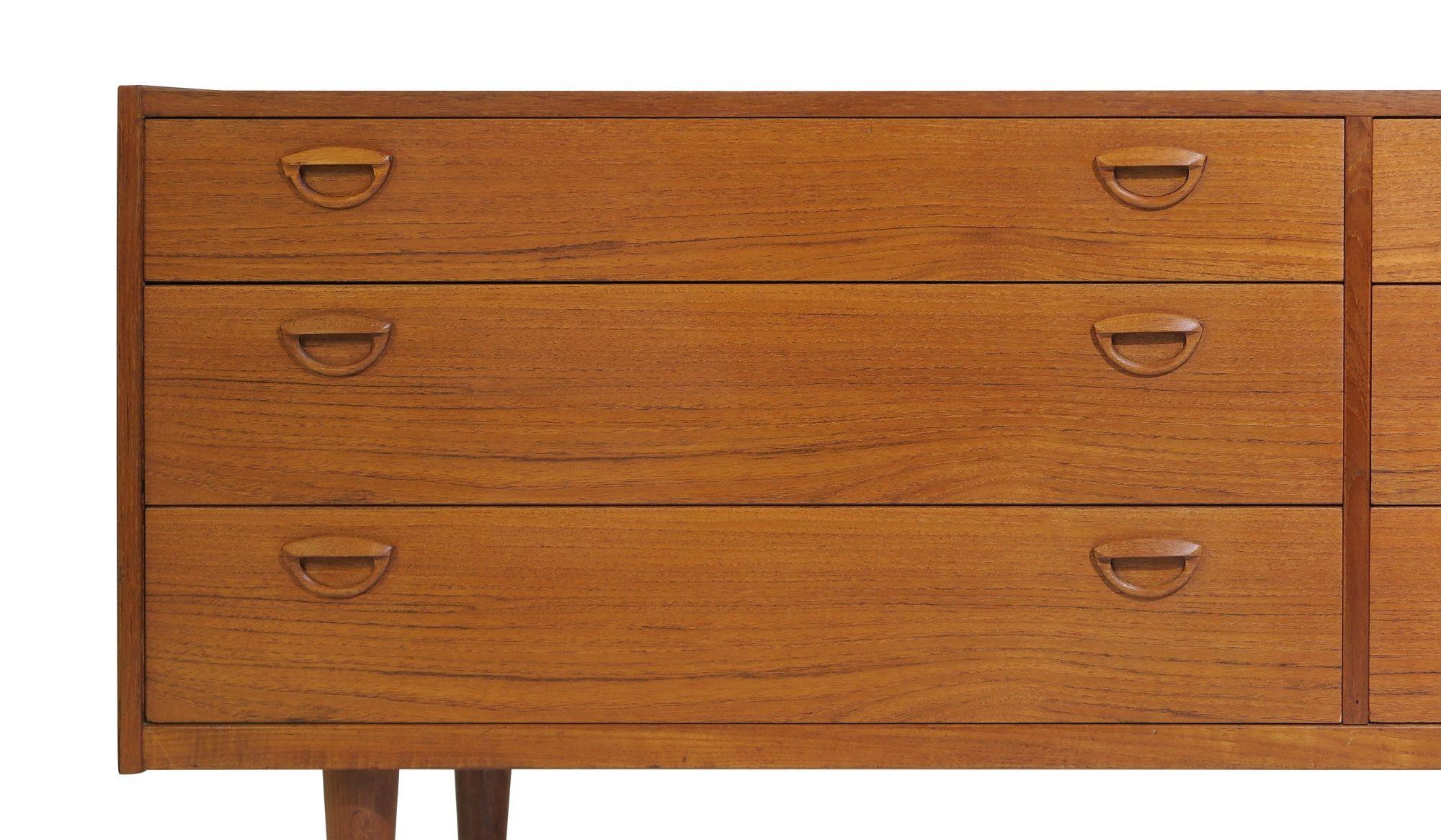 Midcentury Danish teak low dresser designed by Kai Kristiansen, 1955, Denmark. The dresser is crafted of teak with six book-matched drawers and carved pulls, raised on solid teak legs.
Kristiansen's designs are characterized by their simple and