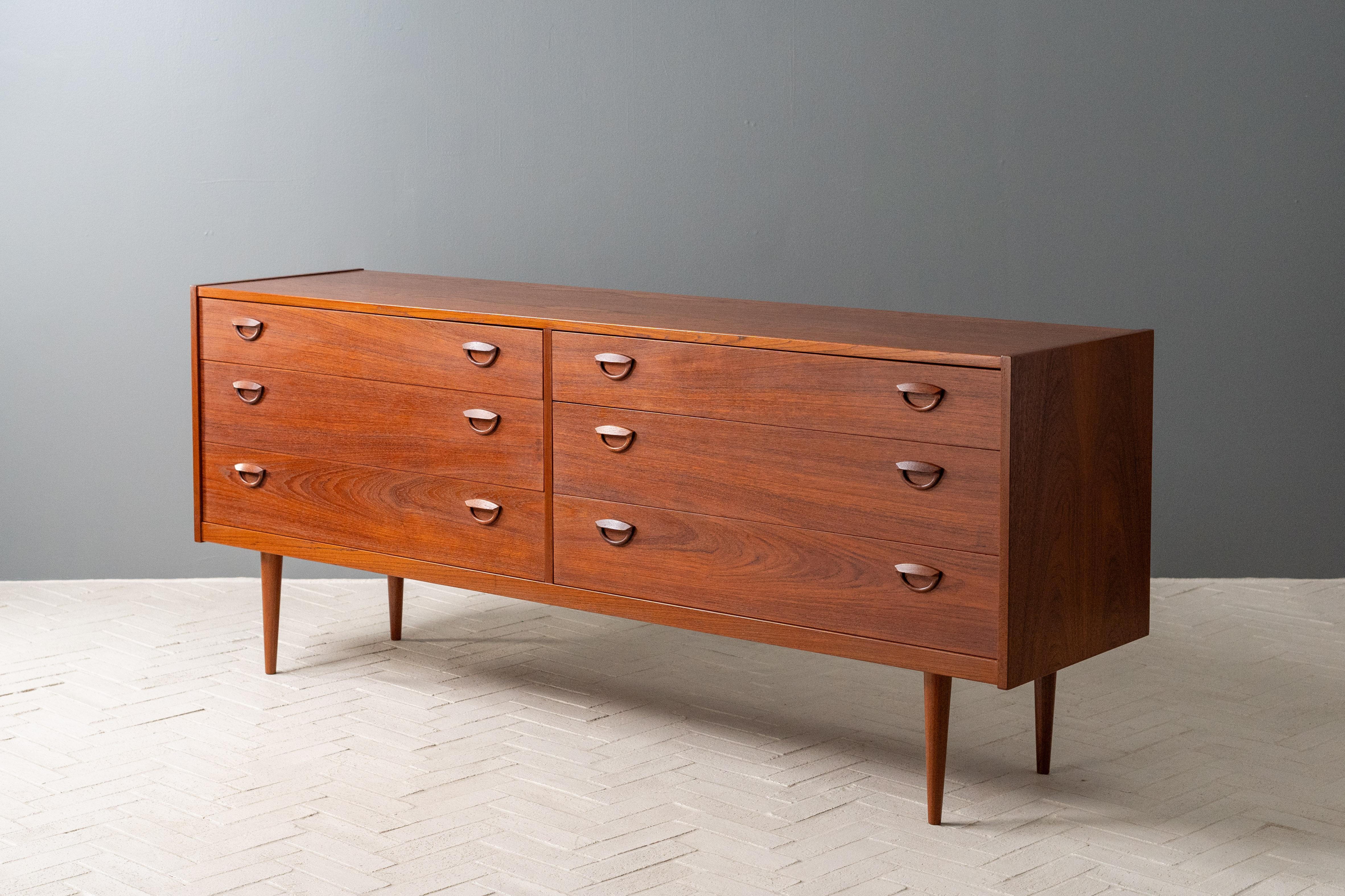 Danimarca, circa anni '50. Un comò basso bello e sempre più difficile da trovare di Kai Kristiansen per Feldballes Møbelfabrik. La struttura è in teak e presenta sei generosi cassetti a coda di rondine, ognuno dei quali è rifinito con i