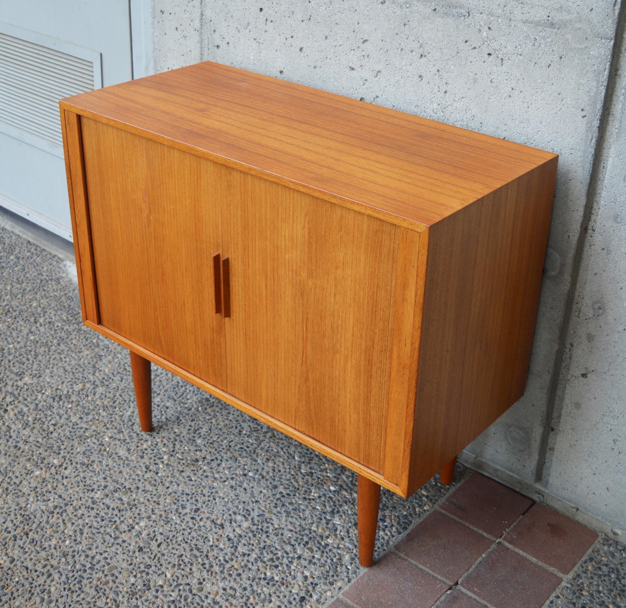 This hot Danish modern teak cabinet / credenza was designed by Kai Kristiansen for Feldballes Møbelfabrik in the 1960s. Featuring tambour doors that disappear inside the cabinet when opened and which have slim contoured door pulls. The interior is
