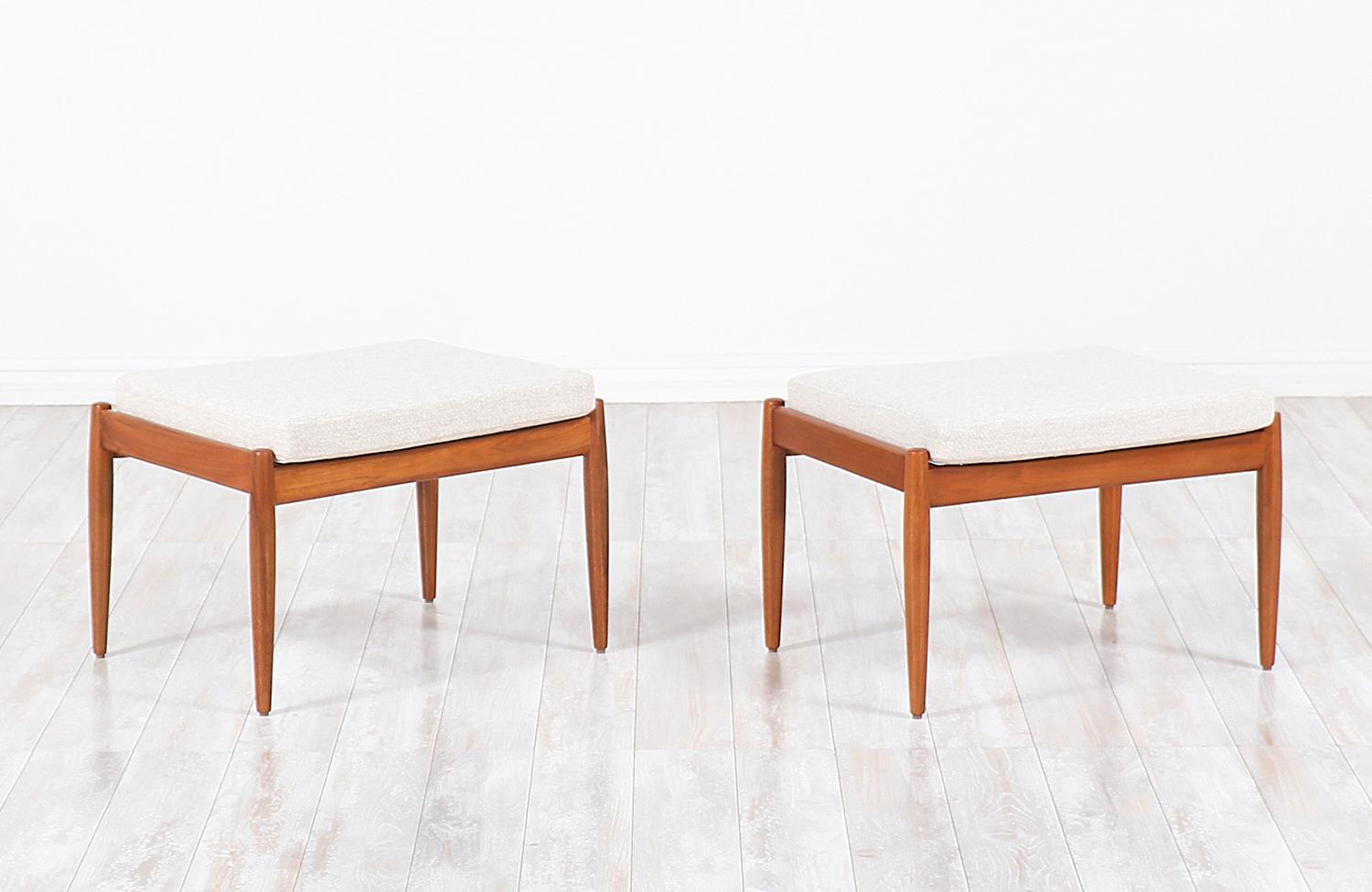 A pair of modern stools designed by Kai Kristiansen and manufactured by Magnus Olesen in Denmark, circa 1960s. These elegant and clean stools feature a teak wood frame with new high-density foam cushions newly upholstered in creamed-colored tweed