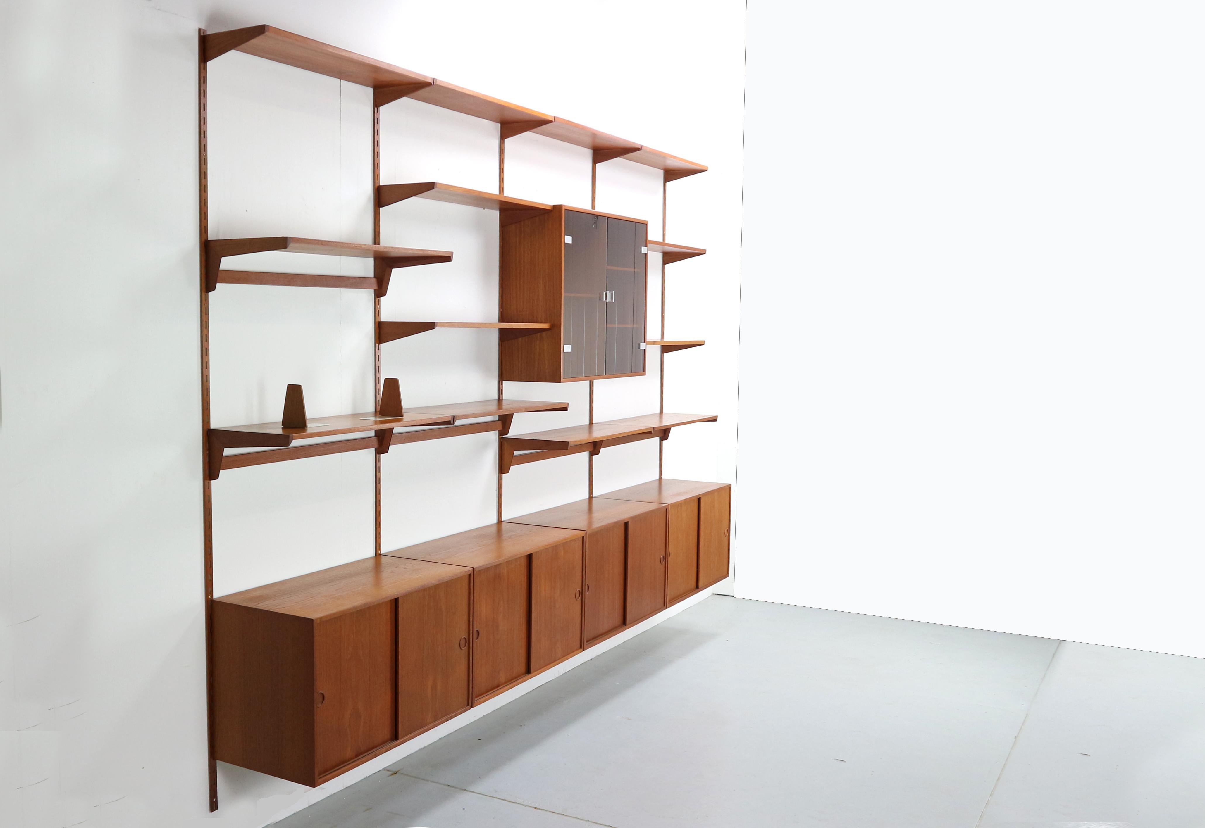 Large teak wood wall unit by Kai Kristiansen for FM Møbler made in Denmark in the 1960s. The cabinets have sliding doors and inside you find shelf's and drawers. The metals bars have a teak veneer and the cabinet is easy to set up, you can adjust