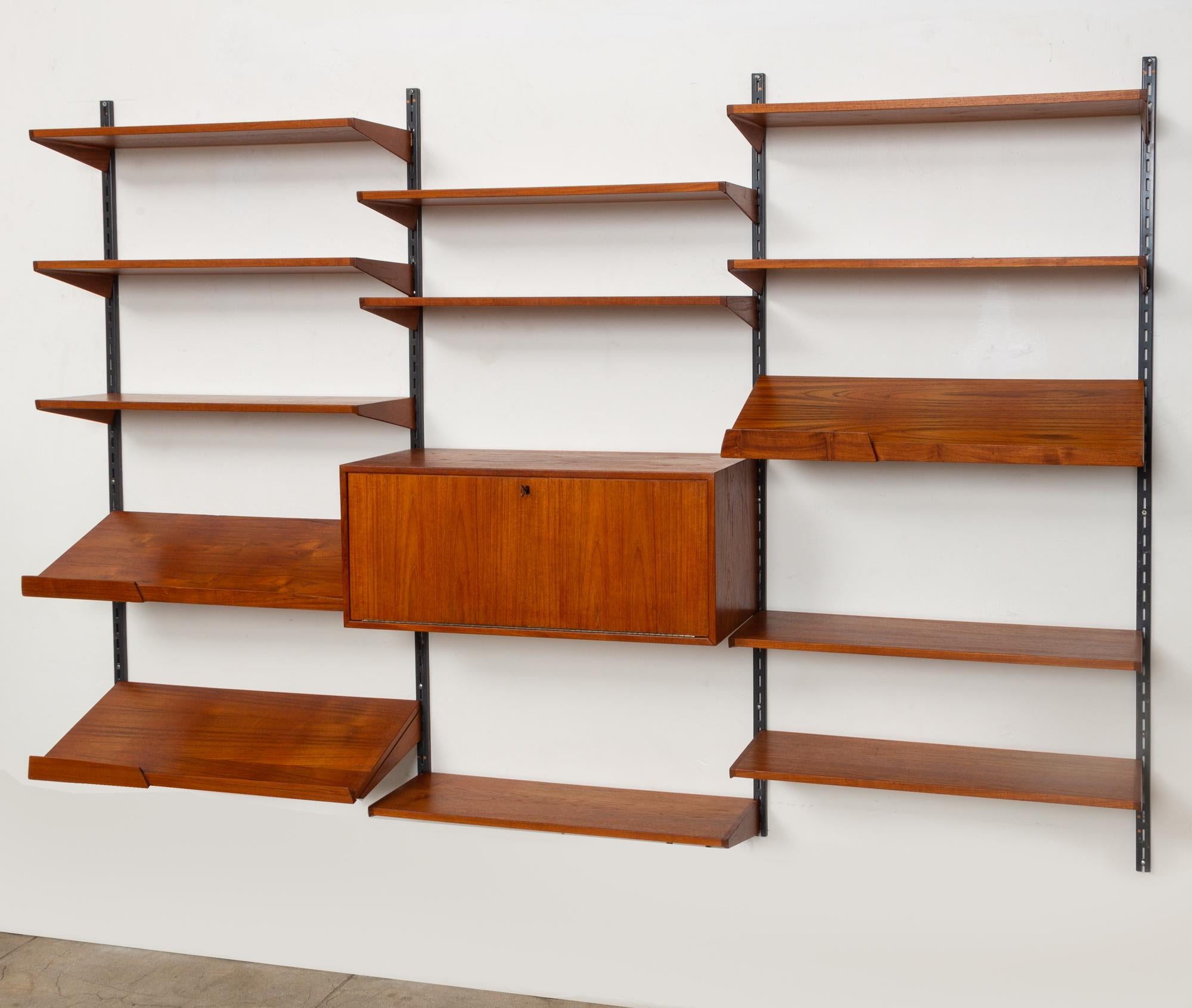Kai Kristiansen wall unit for FM Mobler, Denmark, circa 1960s. This modular shelving system features three bays with steel bars and ten teak adjustable shelves. Also included are three angled magazine shelves and a lockable cabinet, featuring a