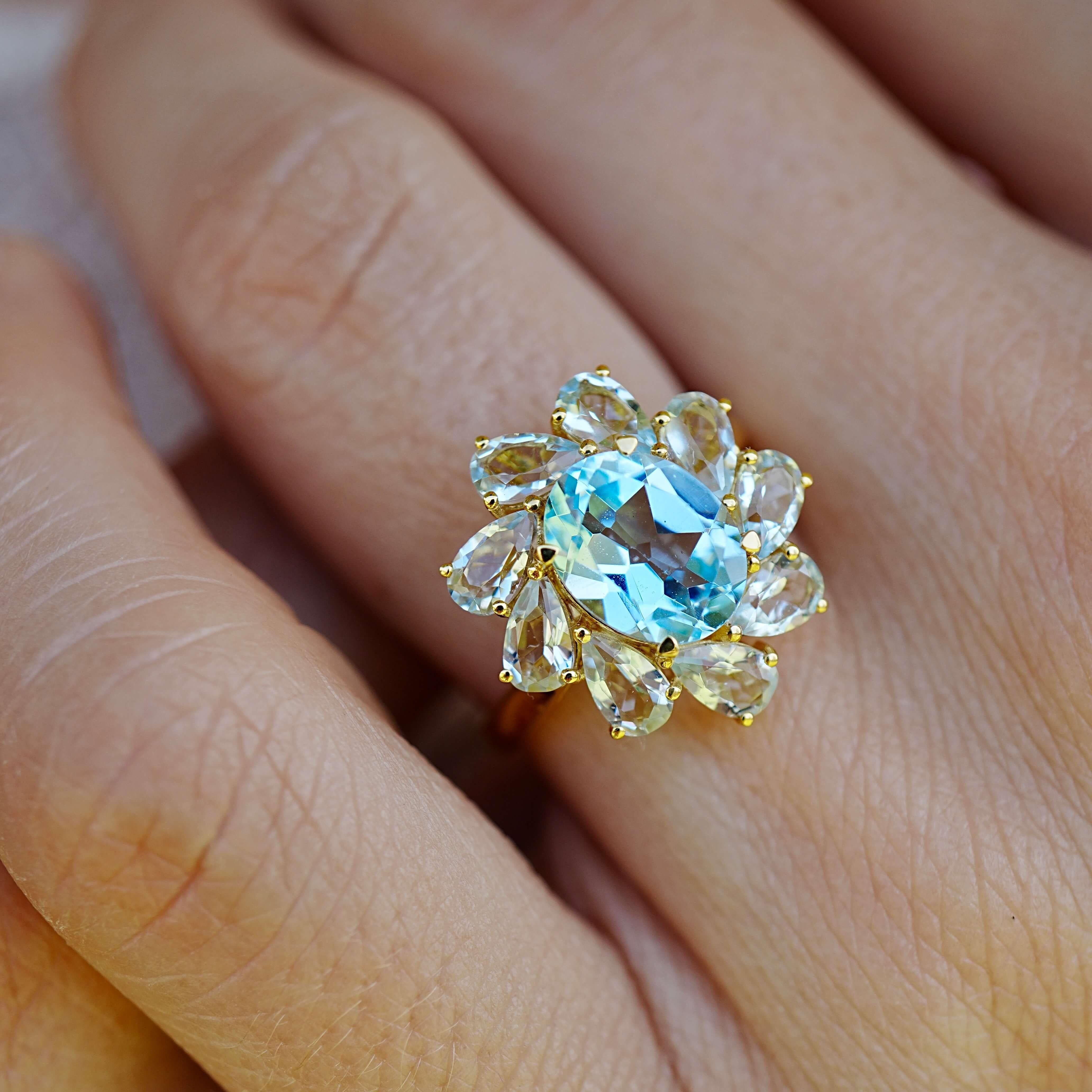 Dieser atemberaubende Cocktailring aus 14-karätigem Gelbgold besteht aus einem Arrangement von 8,60 ct natürlicher Topase und Aquamarine in verschiedenen Schliffen und Farbtönen. In seinem Zentrum befindet sich ein brillanter himmelblauer Topas im