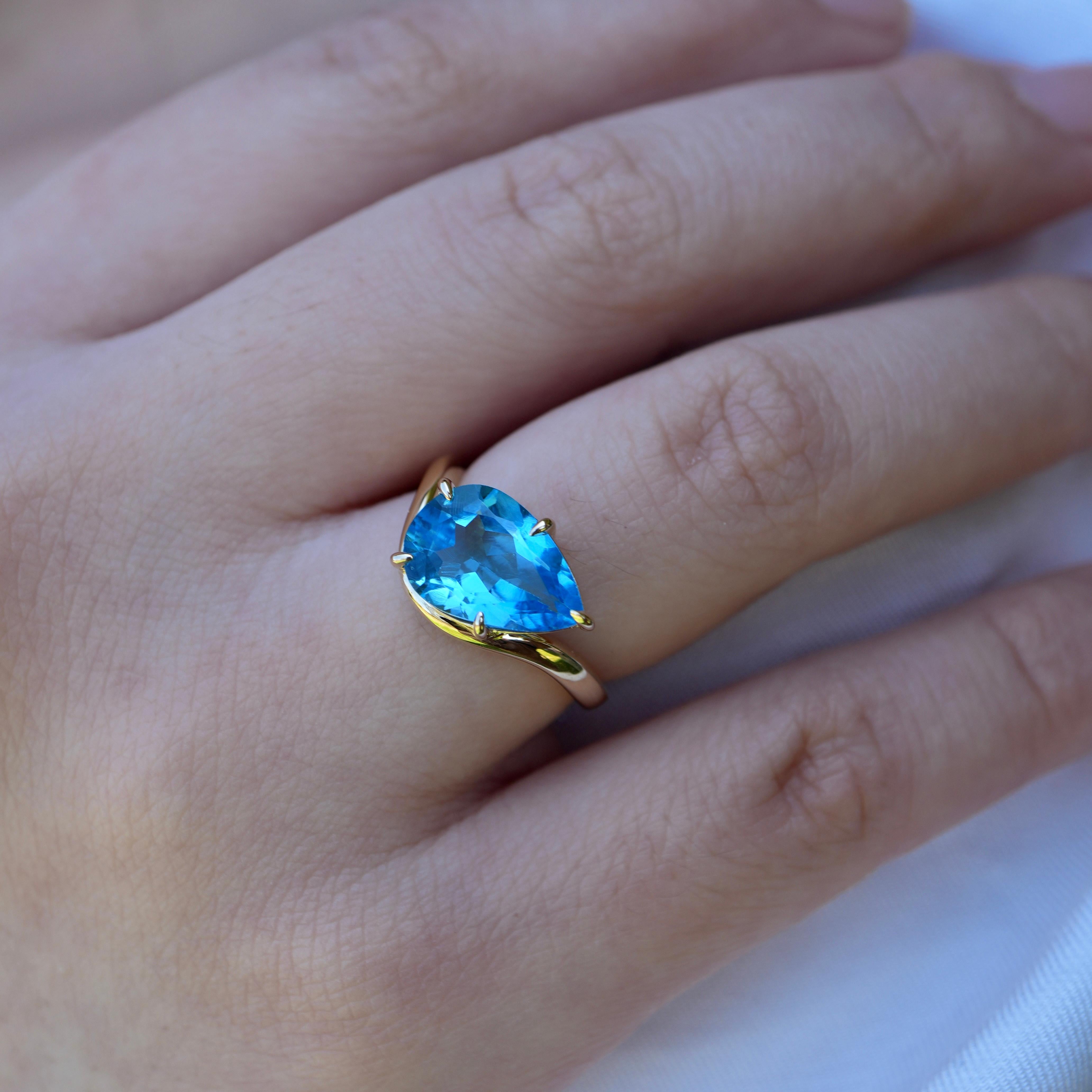 Dive into the calming hues of our Natural Swiss Blue Topaz East-West Ring, set in 14K solid gold. Inspired by the rhythm of ocean waves, the elongated east-west setting showcases a vibrant topaz that glows with serene energy. Whether worn alone or