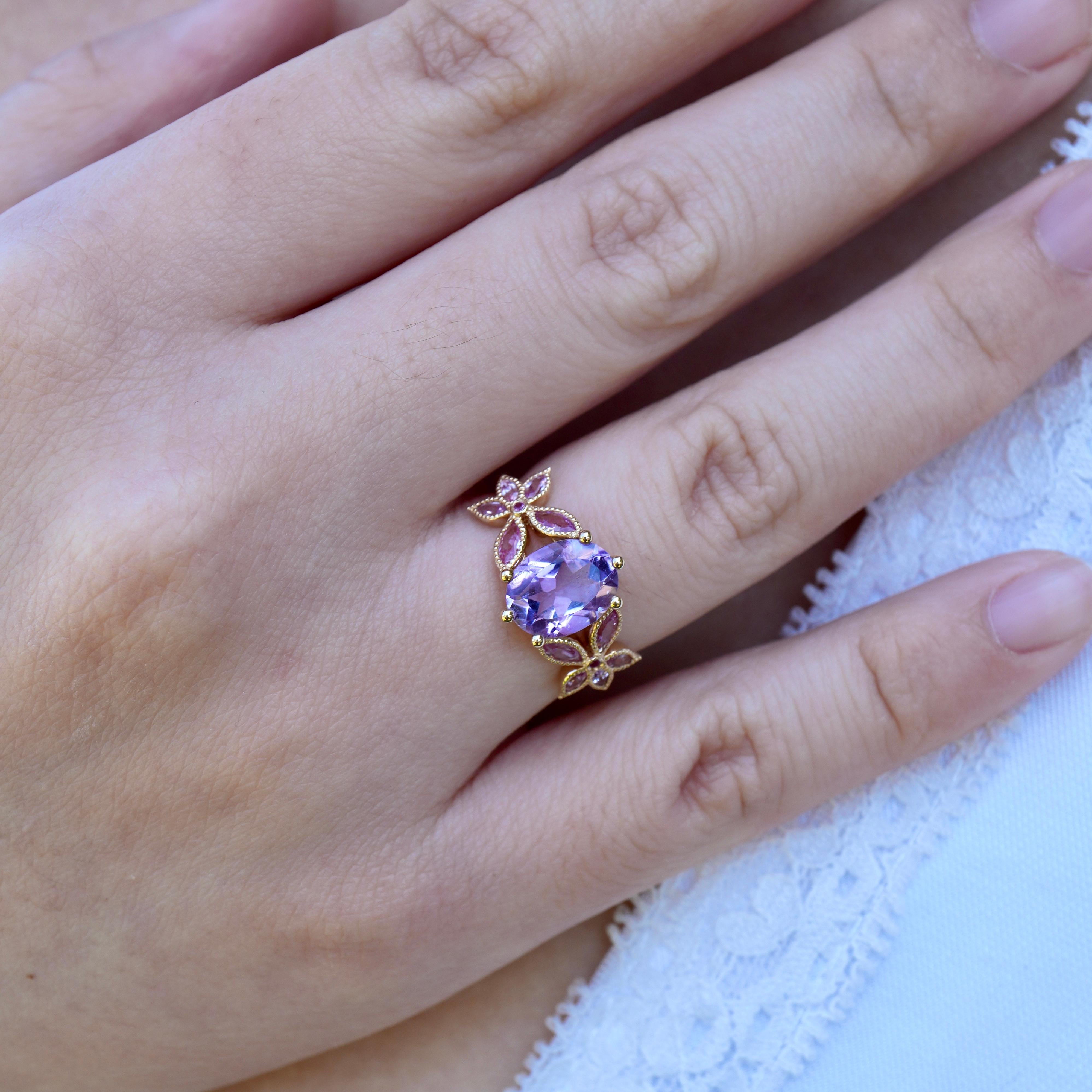 Delicate yet full of character, this 14K solid gold ring showcases a mesmerizing Rose De France lavender amethyst at its center, framed by soft pink sapphires in a floral-inspired silhouette. The blend of pastel gemstones exudes effortless romance