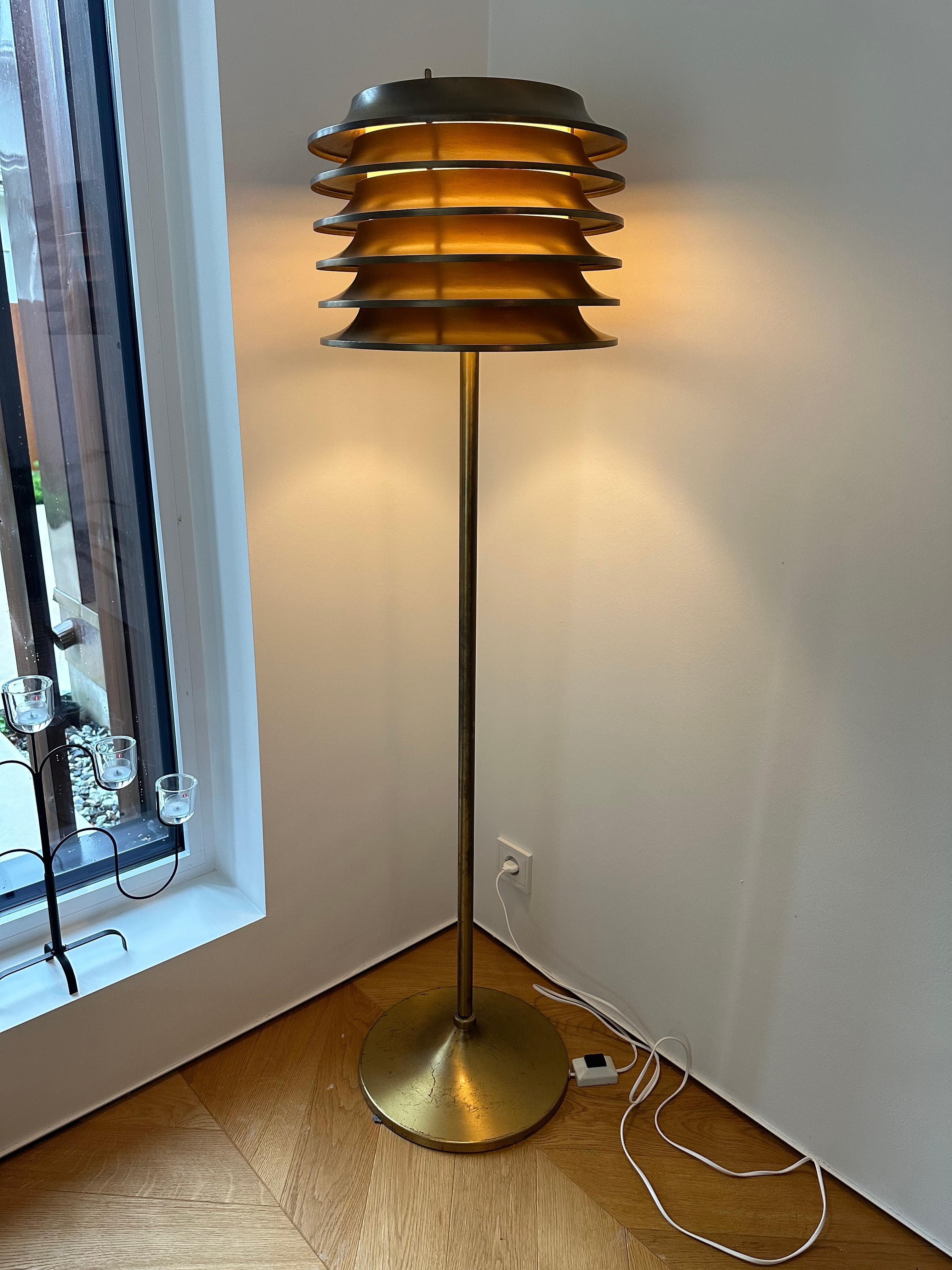 The lamp was designed by Kai Ruokonen (Finnmark) for the Vaakuna Hotel in Helsinki in the 1970s.  A very simple yet elegant heavy duty lamp in full brass with a beautiful patina.


