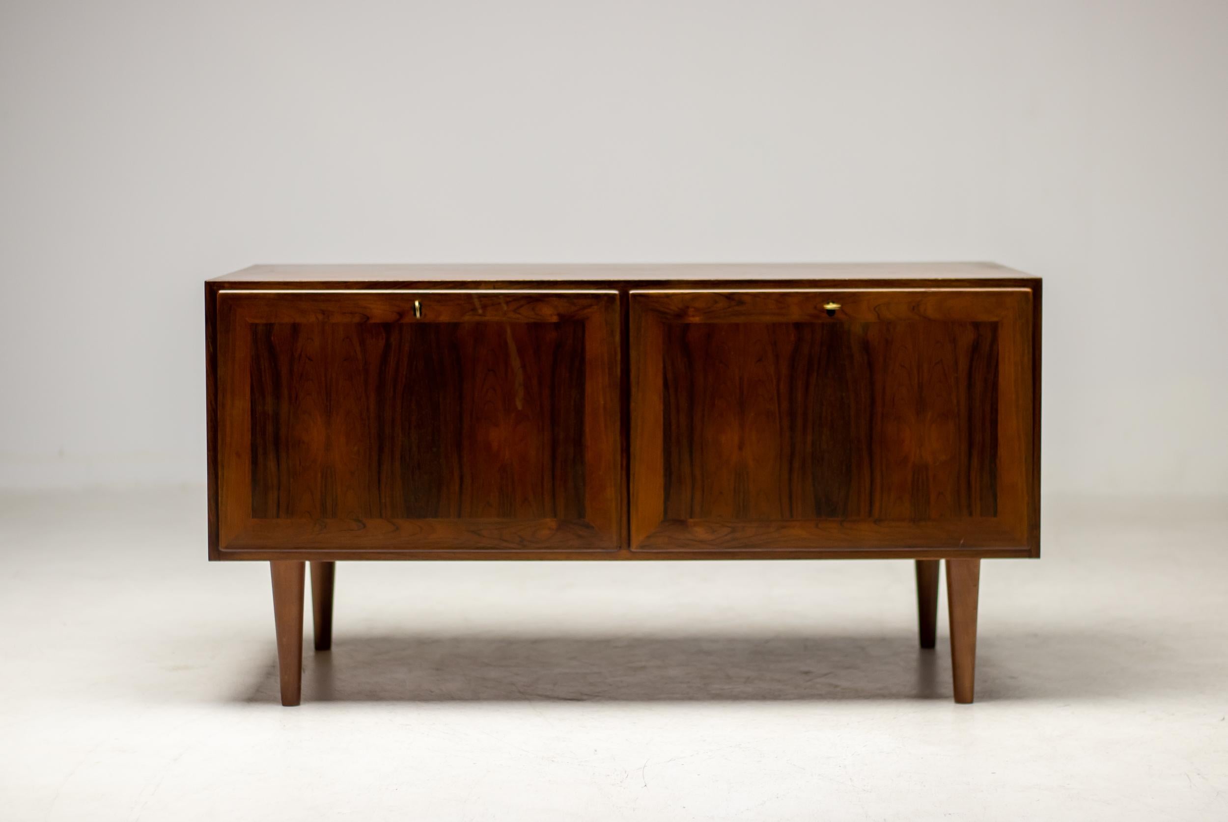 Rosewood sideboard designed by Kai Winding, produced by Poul Jeppesens Møbelfabrik.
The piece has 2 inside drawers with an opening, very suitable for high end stereo equipment storage.
Marked with label.

Kaj Winding is best known for his iconic