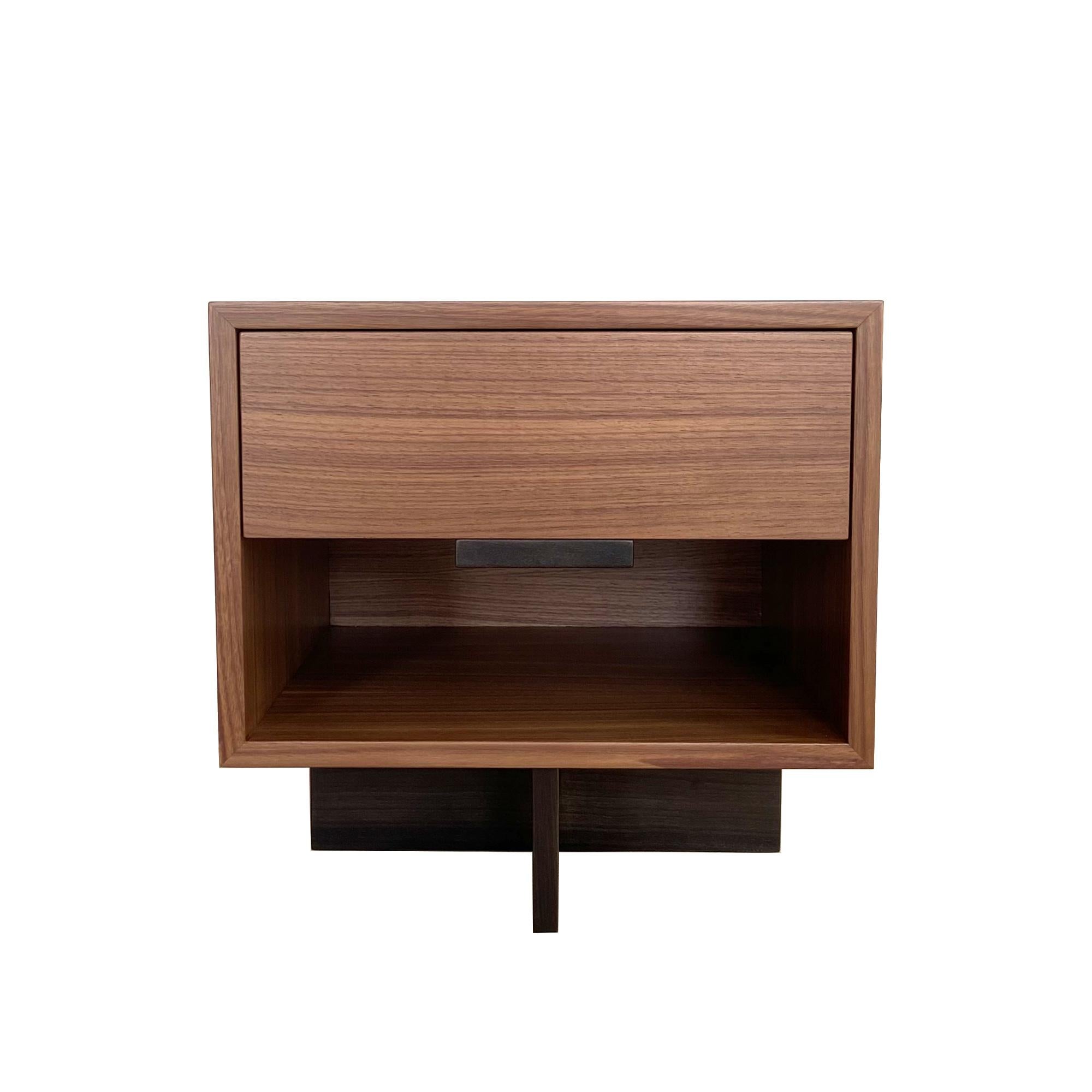 La table de nuit Kaid est un meuble fonctionnel et attrayant qui ajoutera une touche moderne et unique à votre espace de vie.

Le contraste entre l'élément de rangement massif et rectangulaire et le piédestal fin et linéaire donne une impression