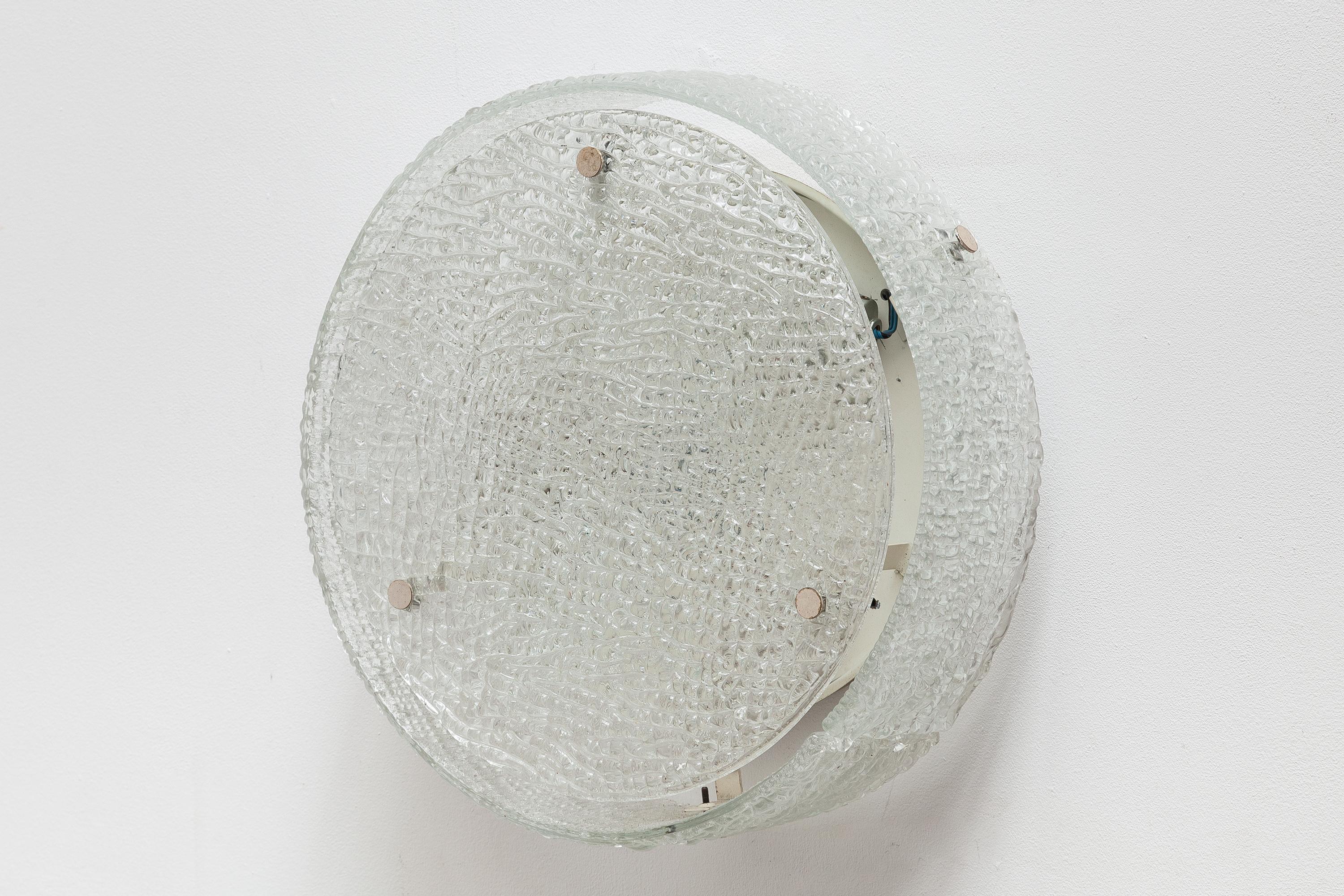 Vintage midcentury wall lamp by Kaiser Leuchten, Germany. Circular ice-cube style glass shade with silver hardware. Lit by 3 bulbs. Measure: Diameter 40 cm.