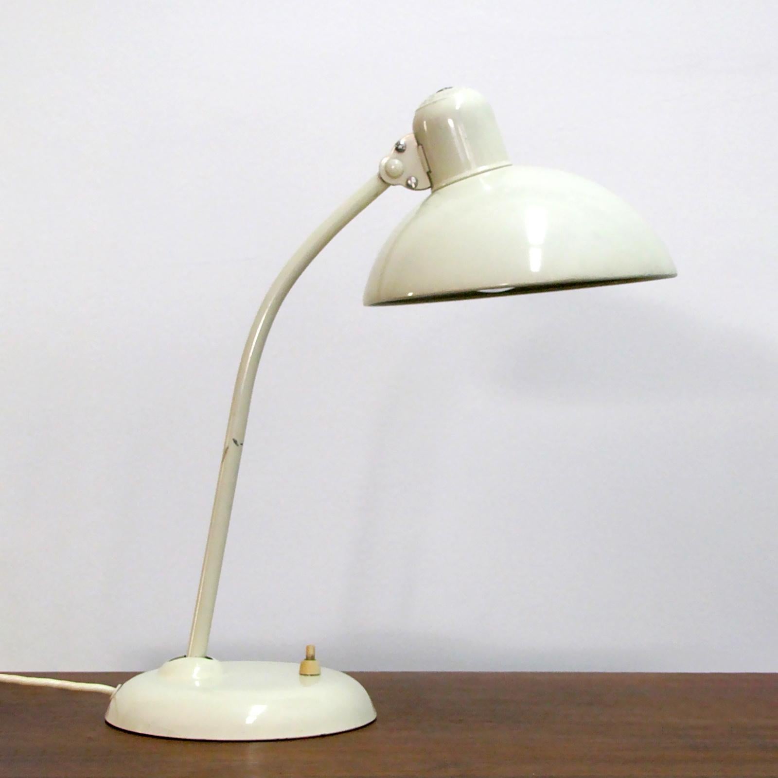 Original ivory enameled steel desk/ task lamps model '6556' by Christian Dell for Kaiser Idell, with a curved pivoting arm and a broad dome shade, marked. Wired for US standards, one E26 socket, max. wattage 75w or LED equivalent, bulb provided as a