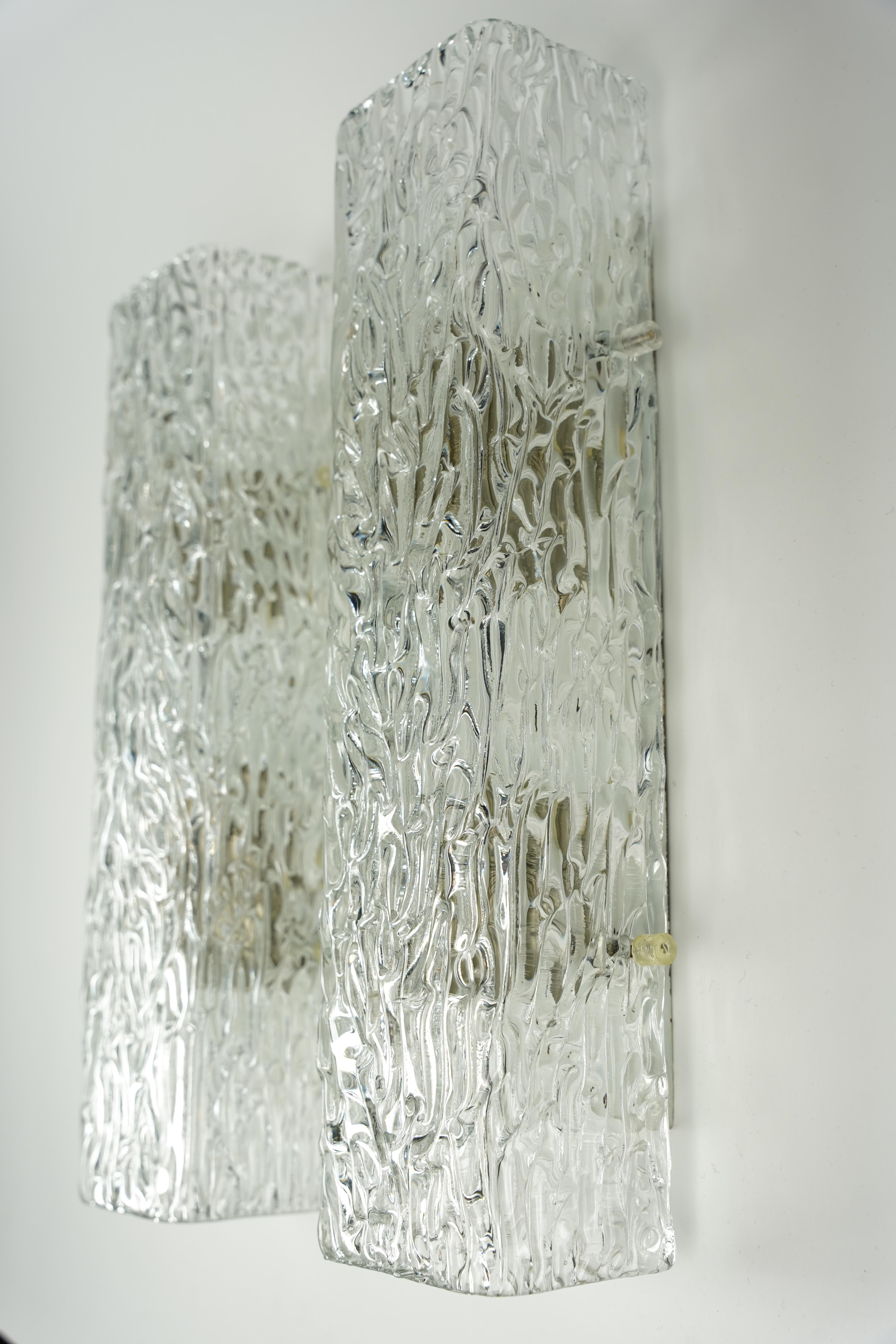 Applique in vetro Kaiser, Germania, 1960, lampade da parete di Kaiser Germania, montatura bianca con paralume in vetro spesso con struttura ondulata trasparente nel vetro, paralume sostenuto da quattro finials, 3 prese a candelabro.



