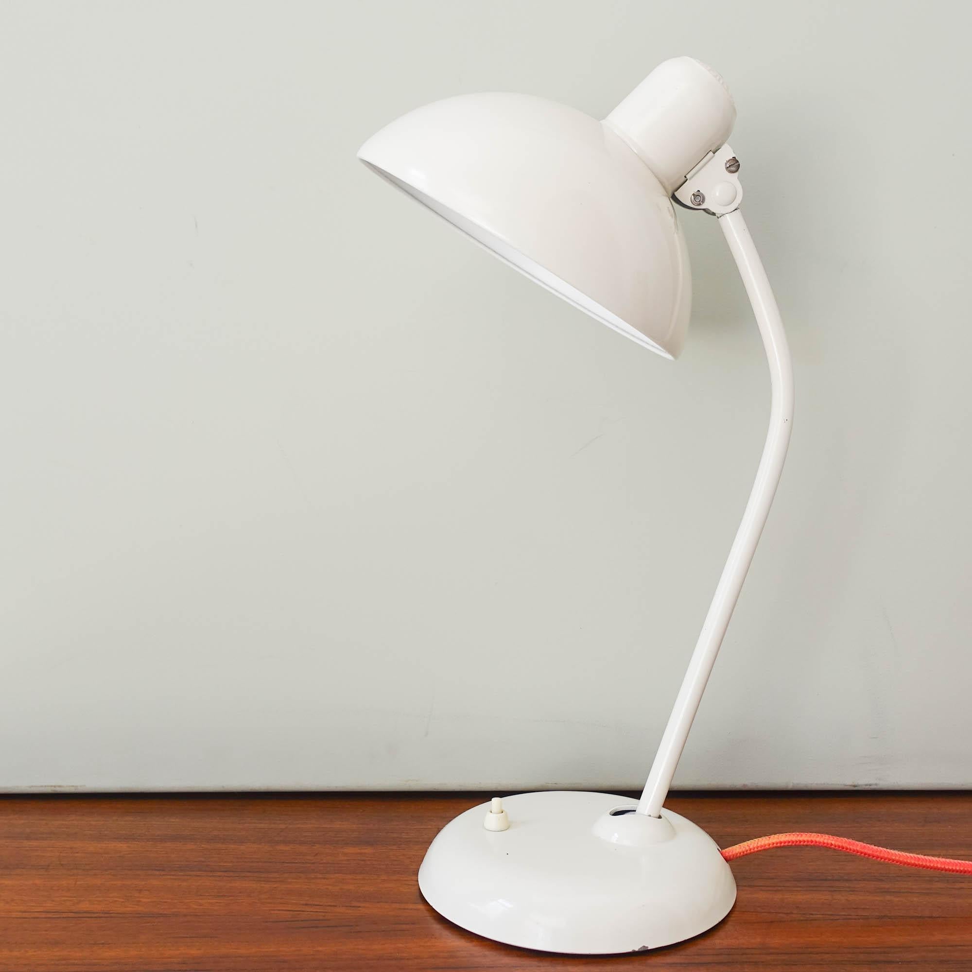 The 6556 model desk lamp was designed by Christian Dell and manufactured by Kaiser Idell, in Germany, during the 1930's. It features an adjustable white lacquered metal shade, with an adjustable white stem, attached to a cast iron base. With