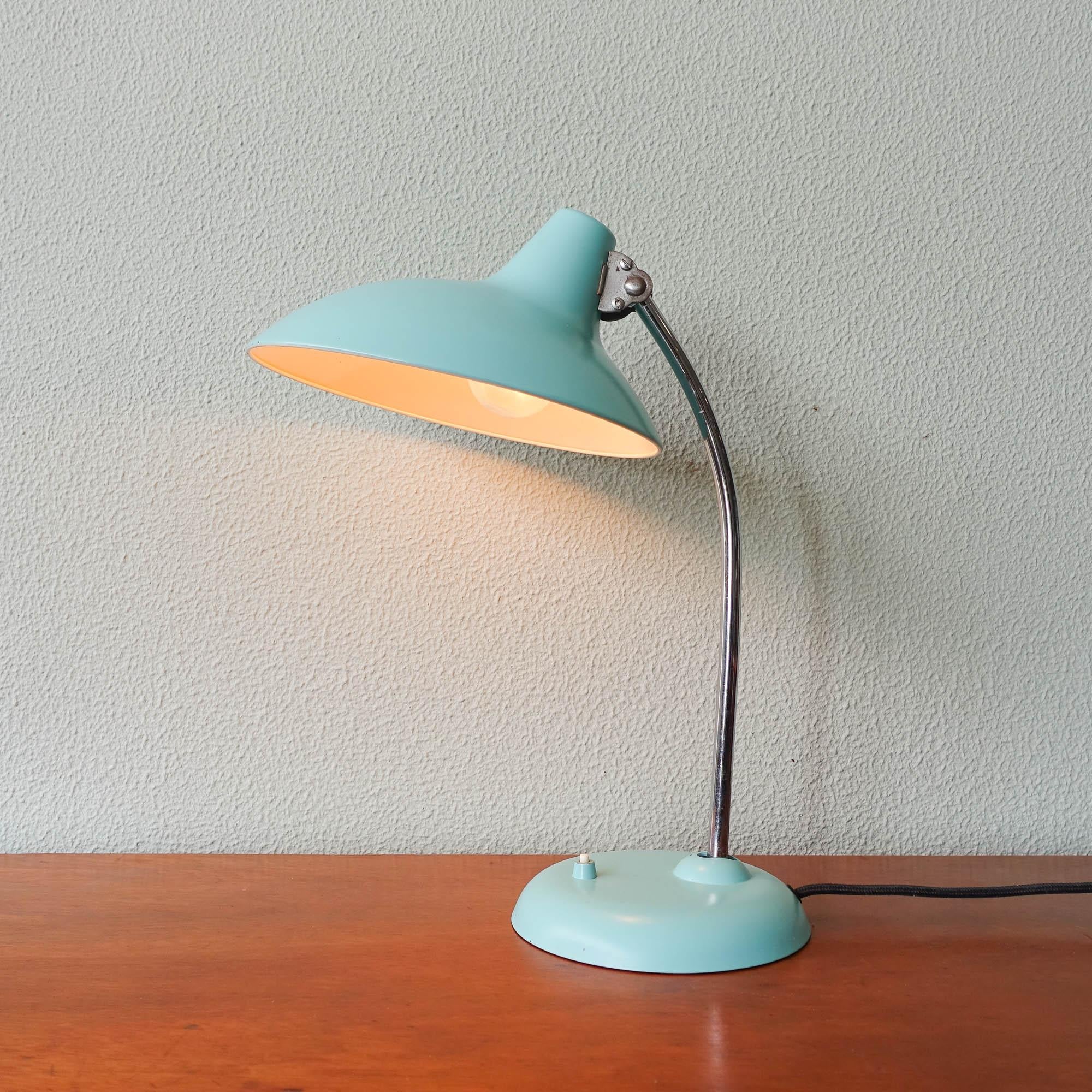 This 6786 model table lamp was designed between 1920-1940 by Christian Dell, and manufactured by Kaiser Idell. It features an adjustable light blue lacquered metal shade, with an adjustable chromed stem. This lamp is in a good vintage condition.