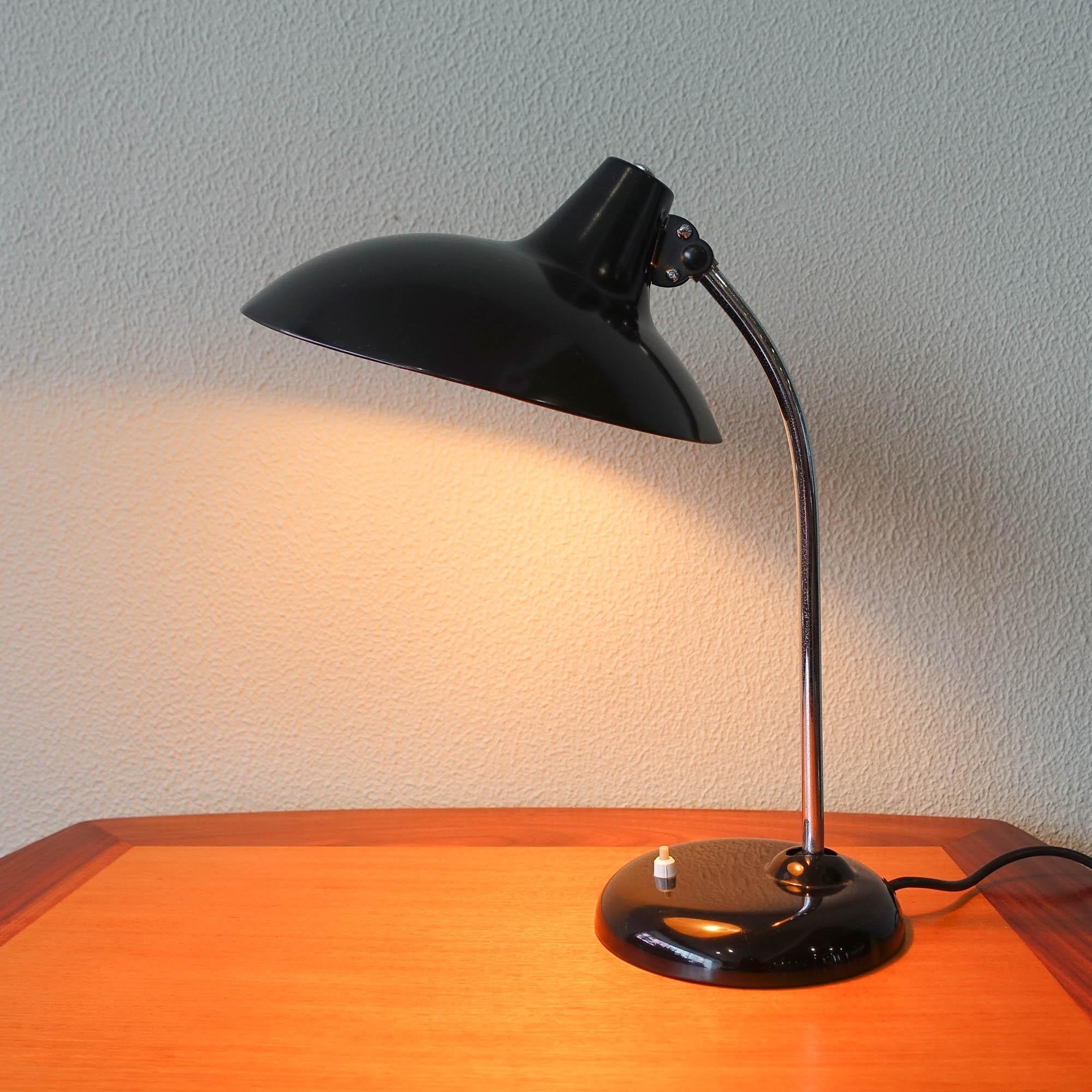 This 6786 model table lamp was designed between 1920-1940 by Christian Dell, and manufactured by Kaiser Idell. It features an adjustable black lacquered metal shade, with an adjustable chromed stem. This lamp was completely restored and it is in a