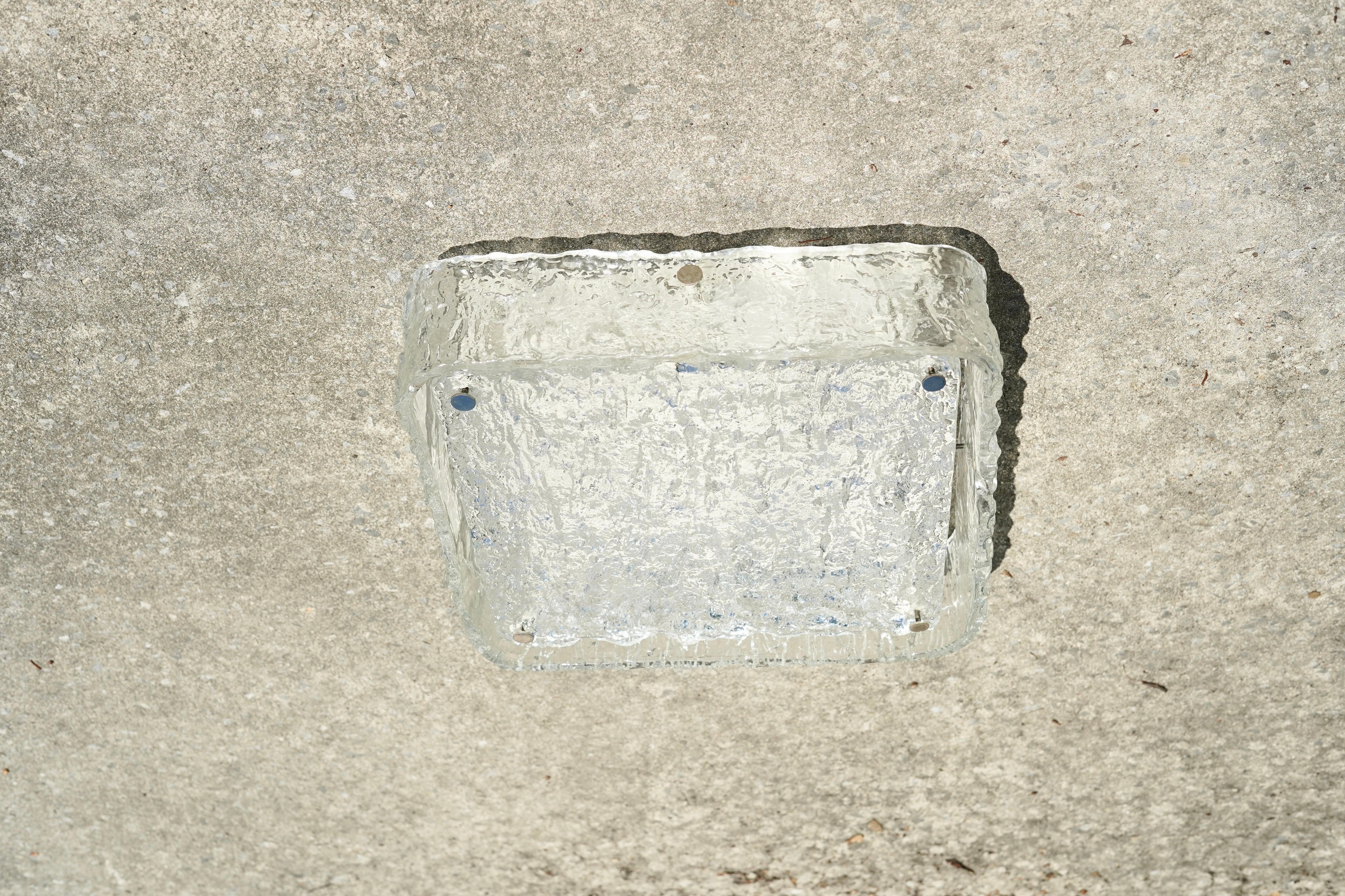 Unterputzleuchte von Kaiser, Deutschland, 1975 quadratischer Klarglasrand, der ein flaches quadratisches Diffusorglas mit Wellenmuster auf einem quadratischen weißen Metallrahmen umgibt. Das Glas wird von acht verchromten Endstücken gehalten.
Vier