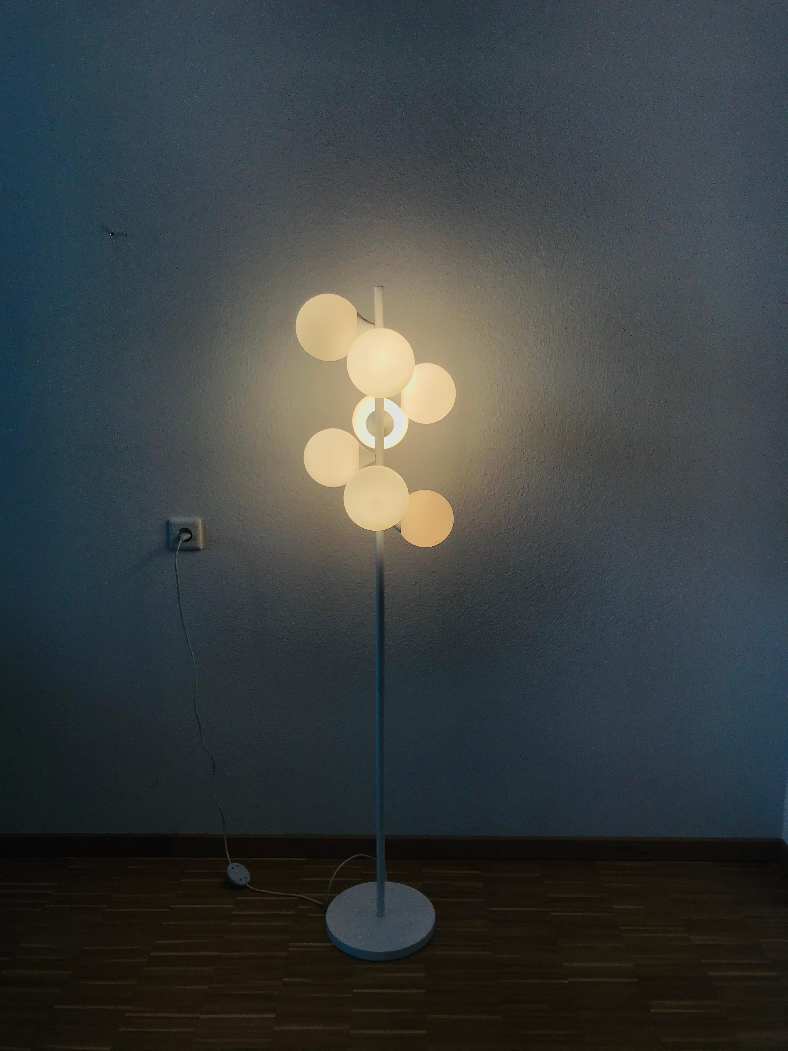A midcentury floor lamp by Kaiser made in Germany in the 1960s. It is fascinating with its Space Age design and seven opaque balls. The white circular body of the light is made of full metal, including the arms.


The light requires seven E14