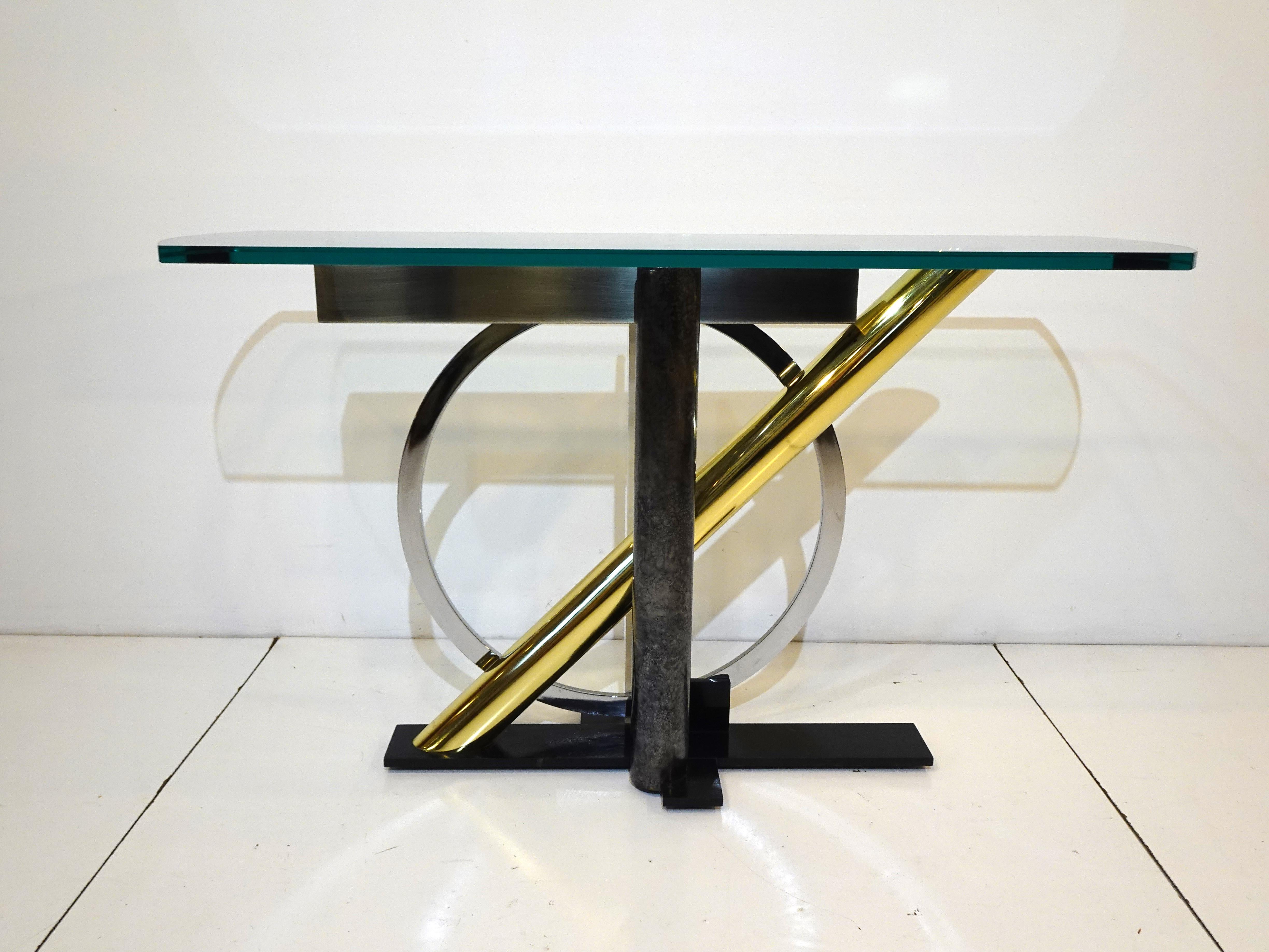 A very well crafted mixed metal console or entrance table with thick plate glass top curved on each end. The metals used are brass, stainless steel, chromed, painted white, black and faux textured silver and grays a great contracting combination of