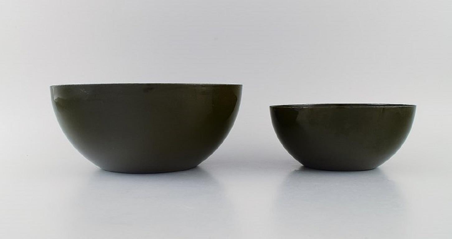 Kaj Franck (1911-1989) pour Finel. Deux bols vert foncé en métal émaillé. 
Design/One, milieu du 20e siècle.
Les plus grandes mesures : 24 x 10,5 cm.
En parfait état. Usure minimale liée à l'âge.
Estampillé.
