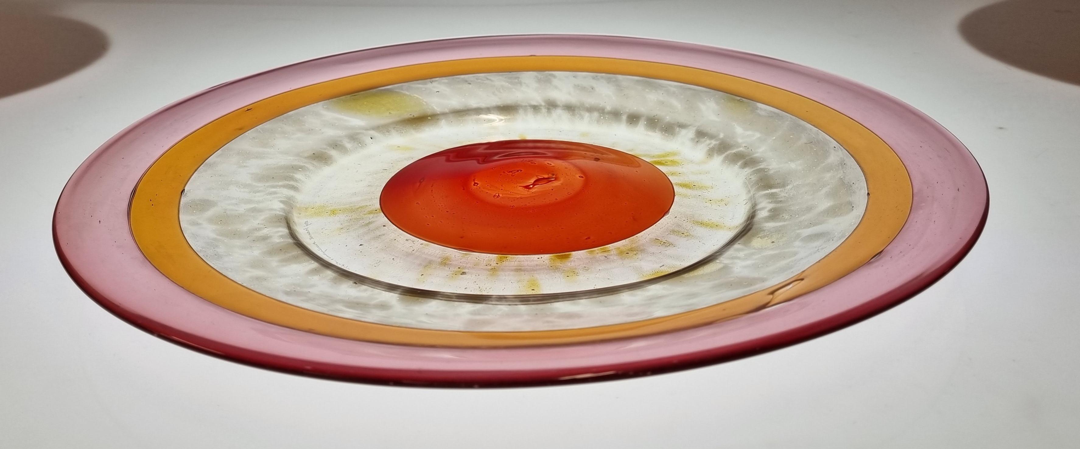 A lovely decorative dish designed by the renowned Kaj Franck. This very colorful design full of red, orange and purple tones blends them all together and creates a vibrant playful vibe. A very simple yet eye catching piece that can bring a whole