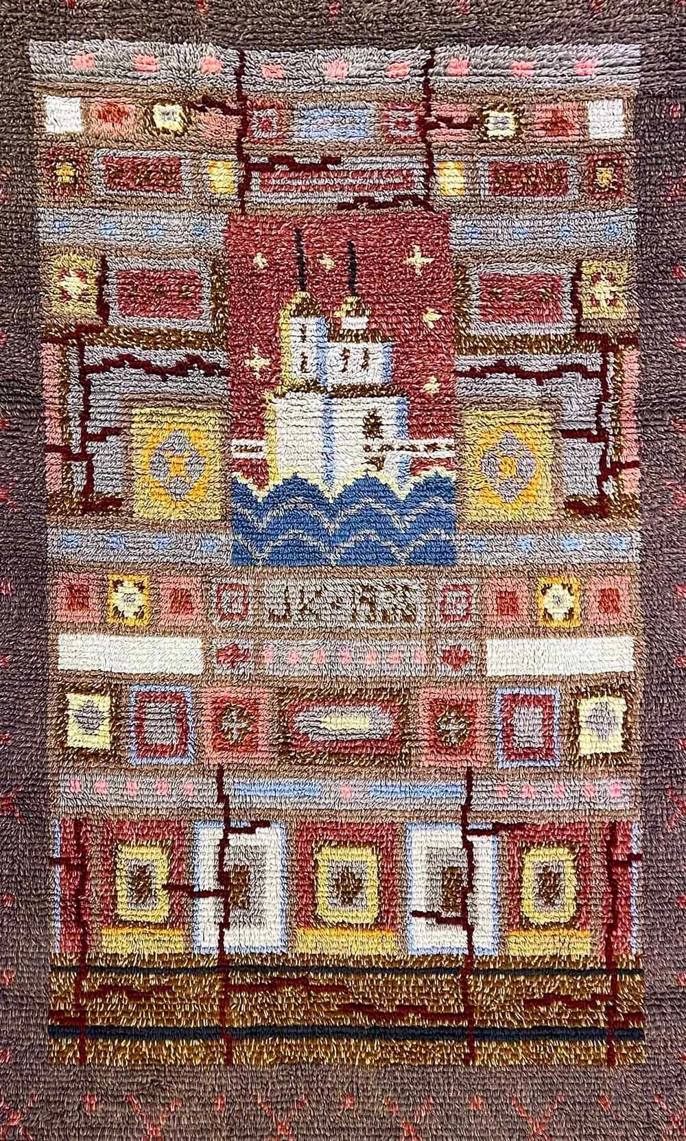 Dieser einzigartige und auffällige Langflor-Ryijy-Teppich wurde von Pia Katerma in Finnland entworfen und zeigt die Burg Kajaani im Zentrum des Wappens von Kajaani, umgeben von geometrischen Mustern und Symbolen in satten, gedeckten Farben -