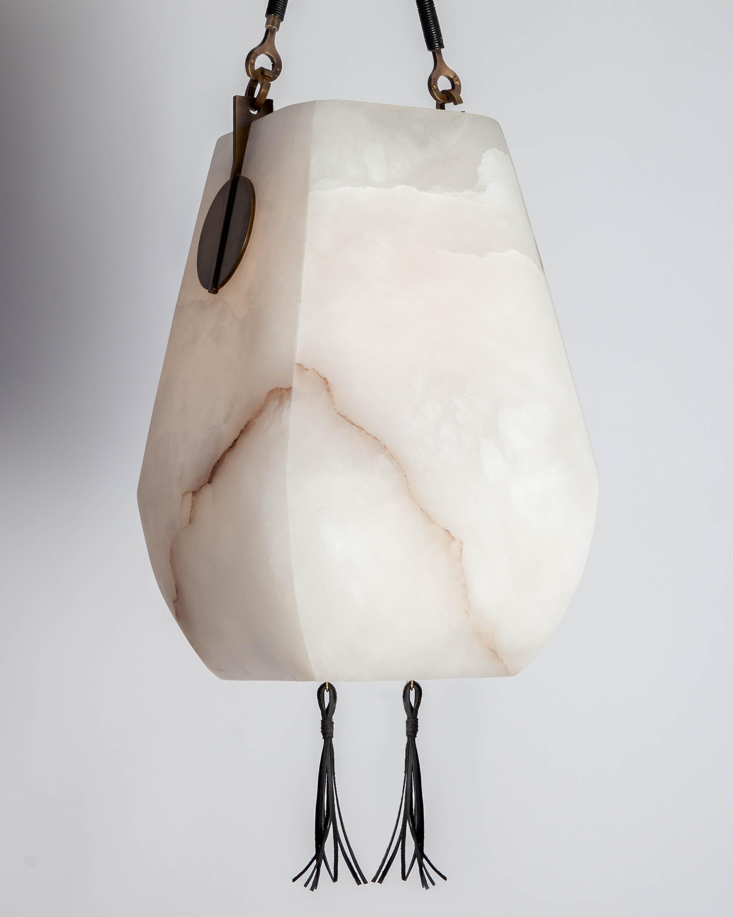 MHL4520
A hanging lantern with a hand-carved, veined white alabaster 'basket' shade, mounted with brass shields and suspended by slender hooks and a milled canopy. Each hook is wrapped in leather cord, and two leather tassels descend through an