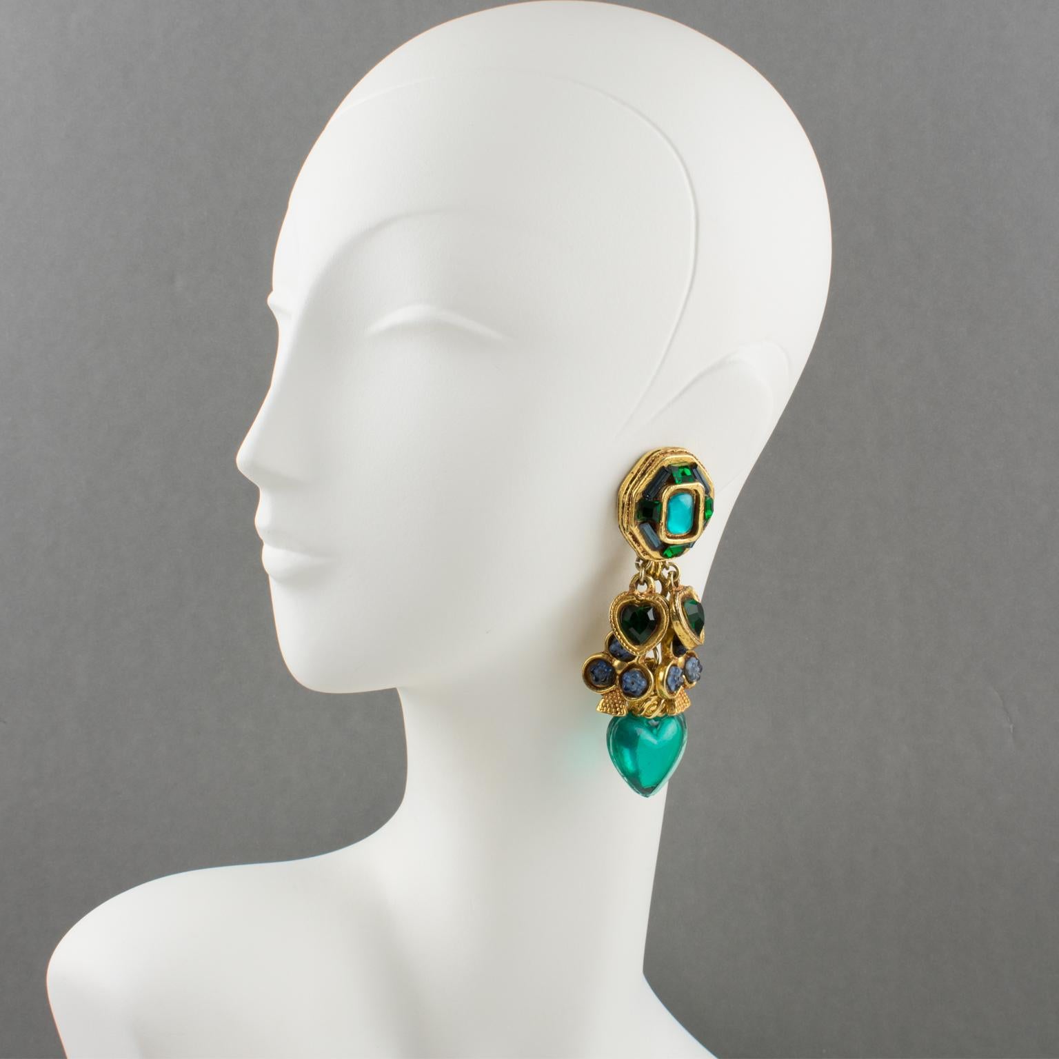 Fabulous Kalinger Paris oversized clip-on earrings. Featuring dangling shape with charms. Gilt-metal coated resin framing with Heart and Club dangling charms along with huge emerald green resin dimensional heart. All elements are ornate with a hue