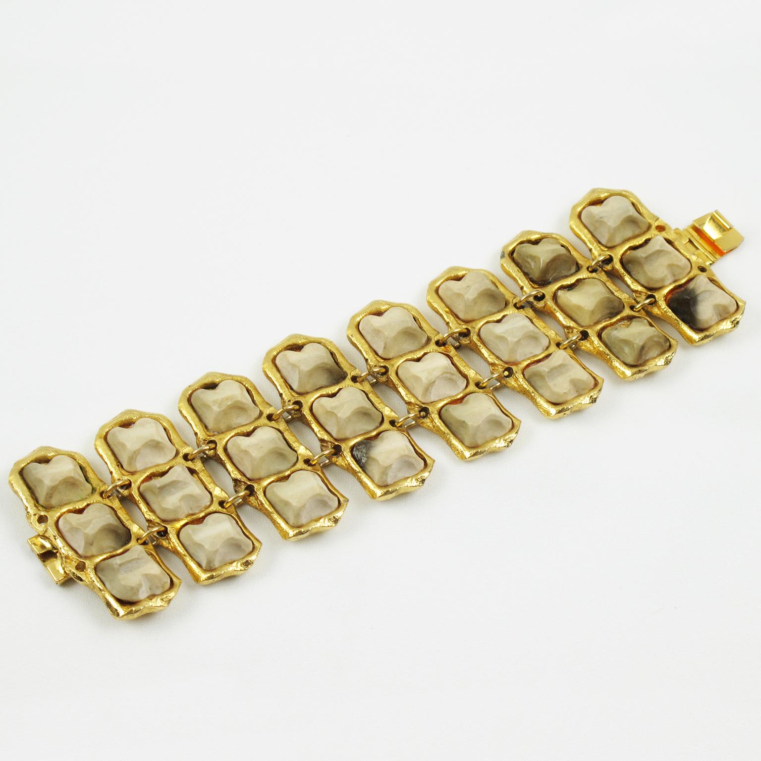 This spectacular Kalinger Paris link bracelet features an oversized and dimensional gilt metal framing with textured, topped with carved resin pebbles in marble-like texture. The metal framing has a satin finish aspect. The resin stones come in a