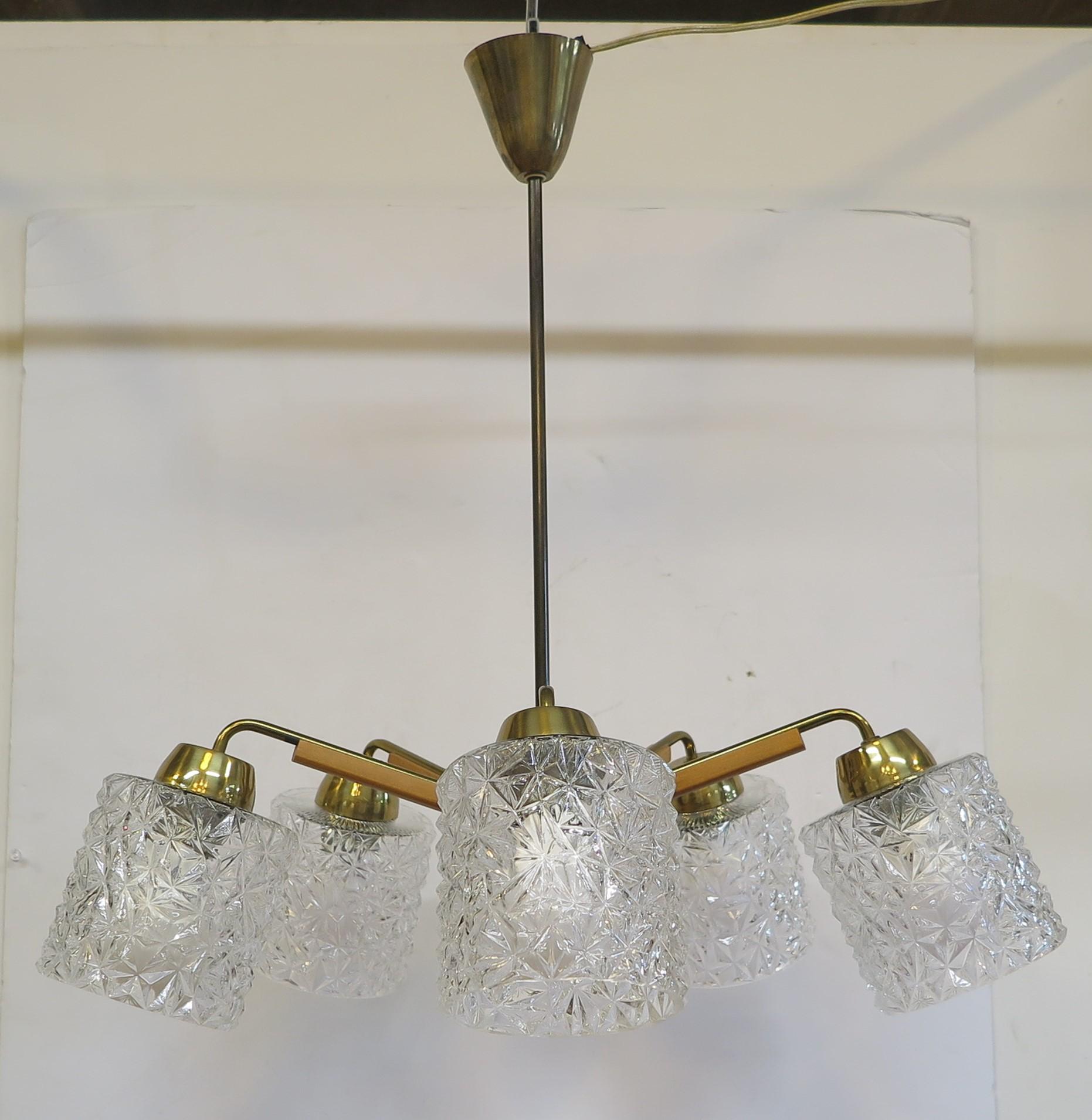 Austrian Chandelier by Kalmar. Brass arms with walnut wood detail supporting pressed molded glass shades. Five arms angled up with shades and light directed down. Snowflake styled patterns molded into the glass cascades, reflects and luminates the