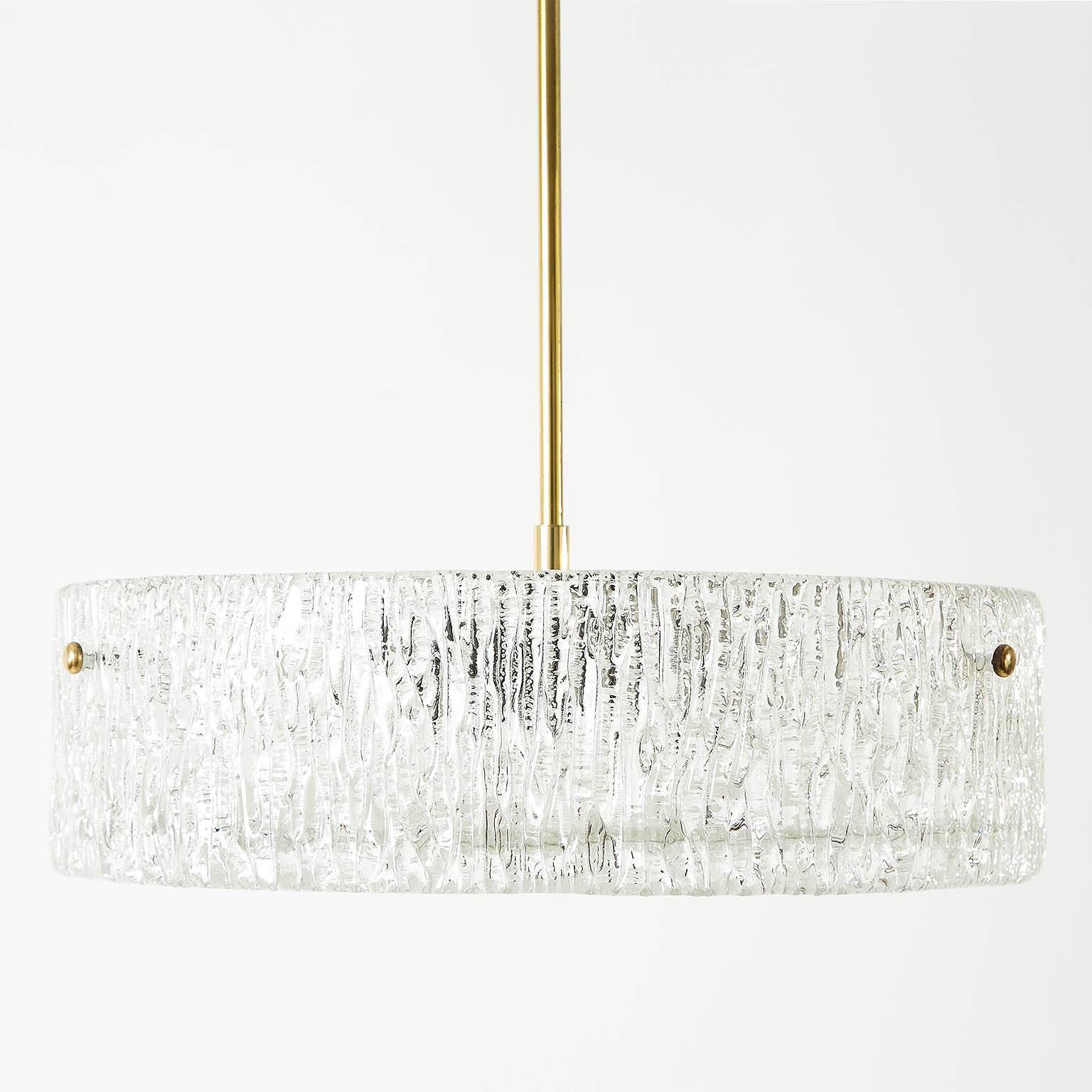 A beautiful textured glass and brass light fixture by J.T. Kalmar, Vienna, manufactured in midcentury, circa 1960 (late 1950s or early 1960s).
A round glass ring is mounted with three brass bolts on a white enameled metal frame. A textured glass