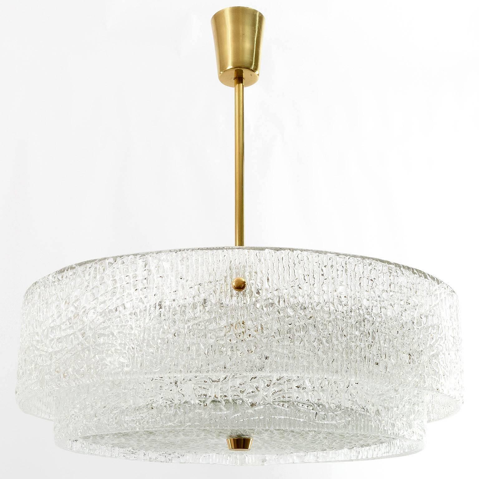 A beautiful textured glass and brass light fixture by J.T. Kalmar, Vienna Austria, manufactured in midcentury, circa 1960 (late 1950s or early 1960s).
Two round glass belts are mounted on a white enameled metal frame. A round glass disk is held by