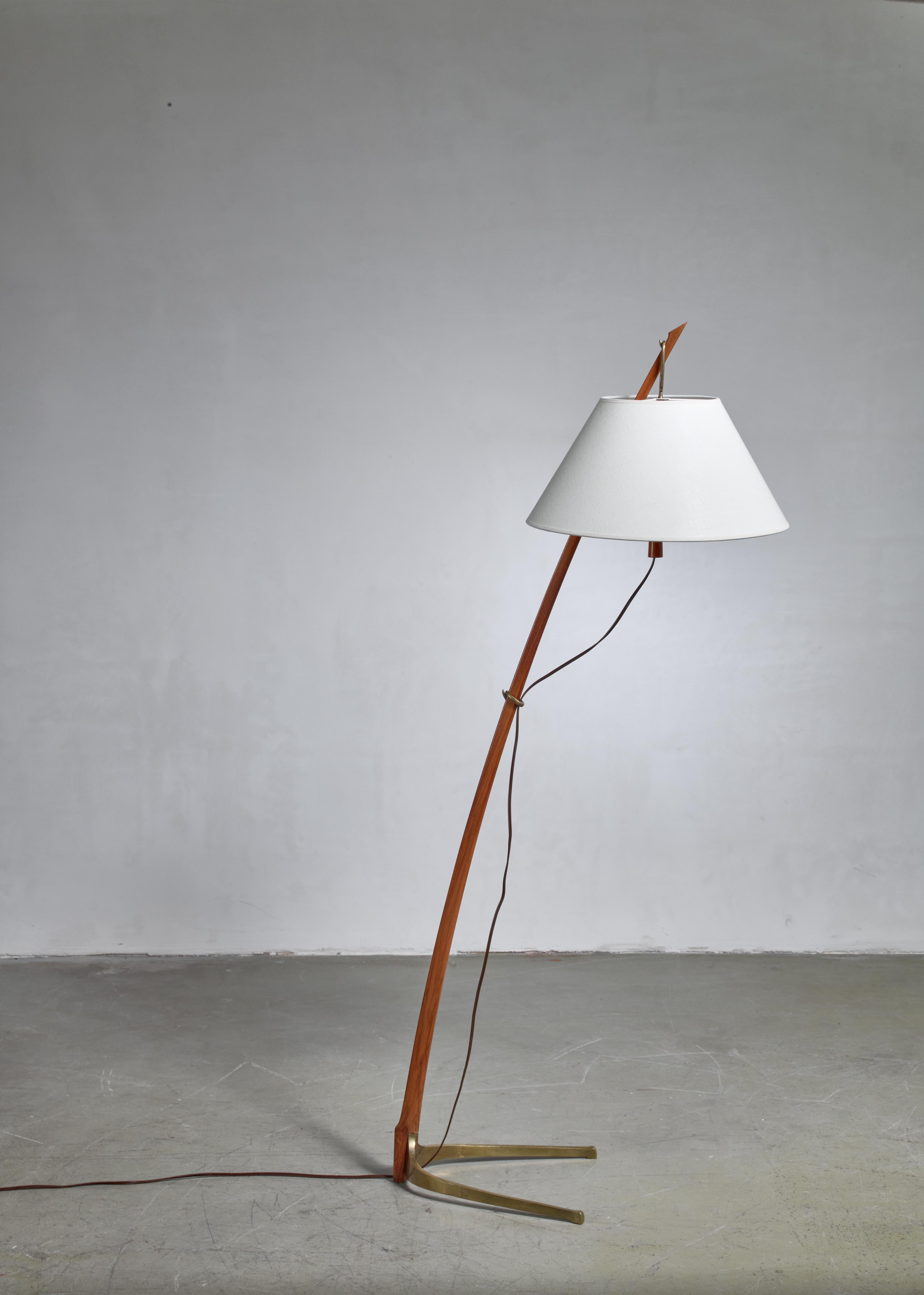 A beautiful Dornstab (‘thorn stick’) floor lamp, designed in 1947 by J.T. Kalmar. It is made out of a wooden, saber shaped stem with a curved brass base and fabric shade. The height of the shade is adjustable to three different positions on the