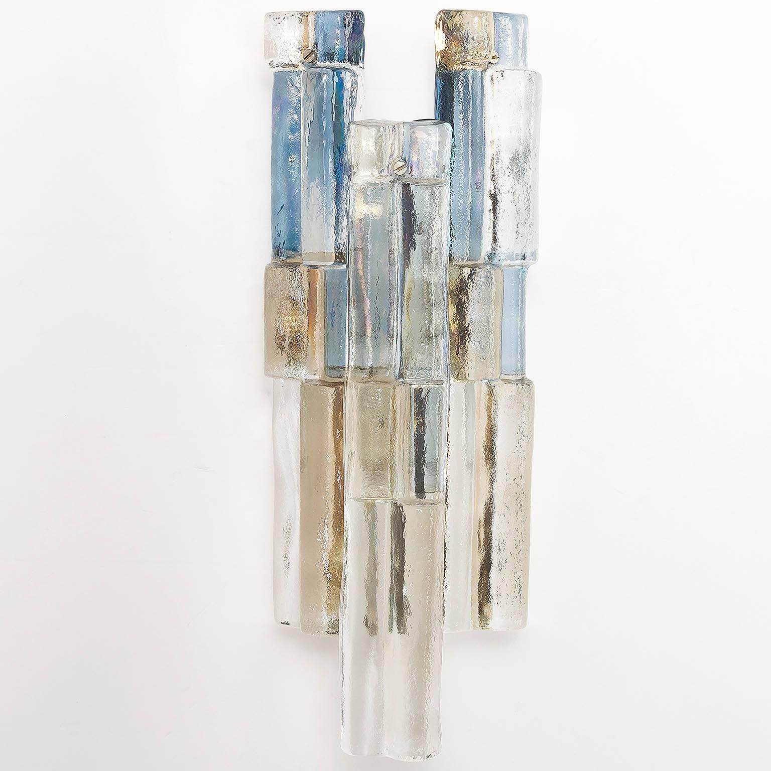 A gorgeous and rare pair of wall lights by Austrian lighting manufacturer Kalmar, manufactured in midcentury, circa 1970.
Multicolored (blue, smoke, amber) glass elements are suspended on a white lacquered metal backplate.
Each sconce has one