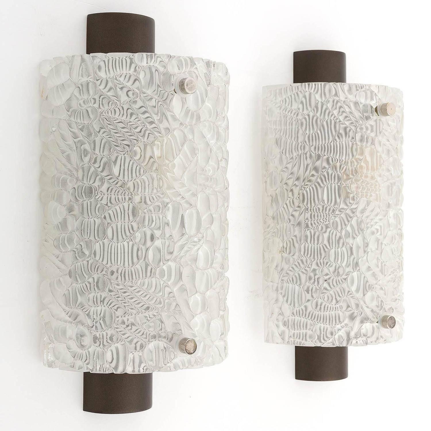A pair of glass sconces or wall lights by Kalmar, Vienna, Austria, manufactured in Midcentury, circa 1960 (late 1950s or early 1960s).
A curved textured glass is mounted on a satin dark brown metal frame. Each light has one socket for a medium base
