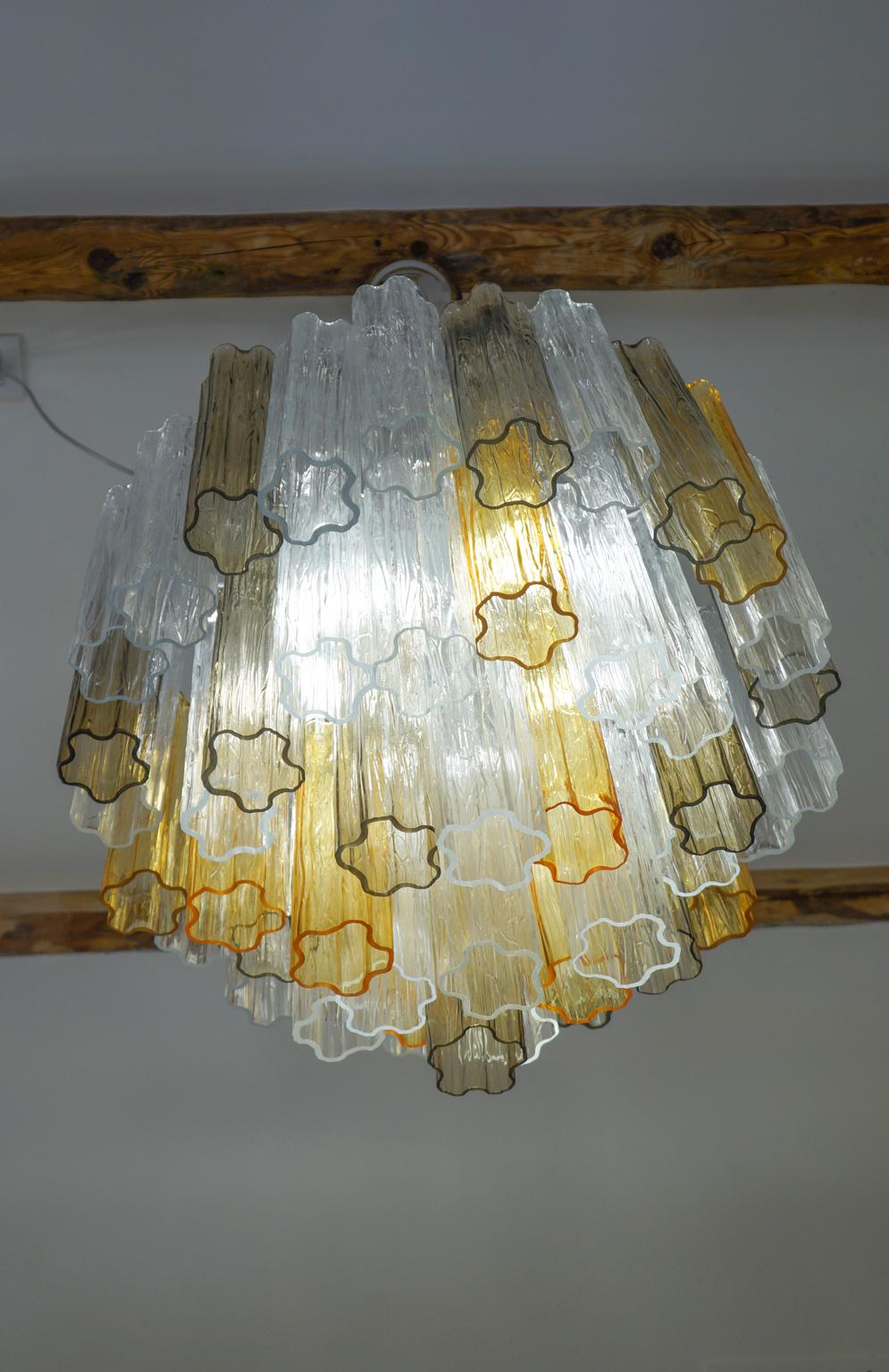 The chandelier you see in the photo is a vintage chandelier, designed in 1980 by Kalmar. It is composed of 49 elements called pipe-trunks and inside we find 5 bulbs that create wonderful play of light reflecting the transparency of the glass. At