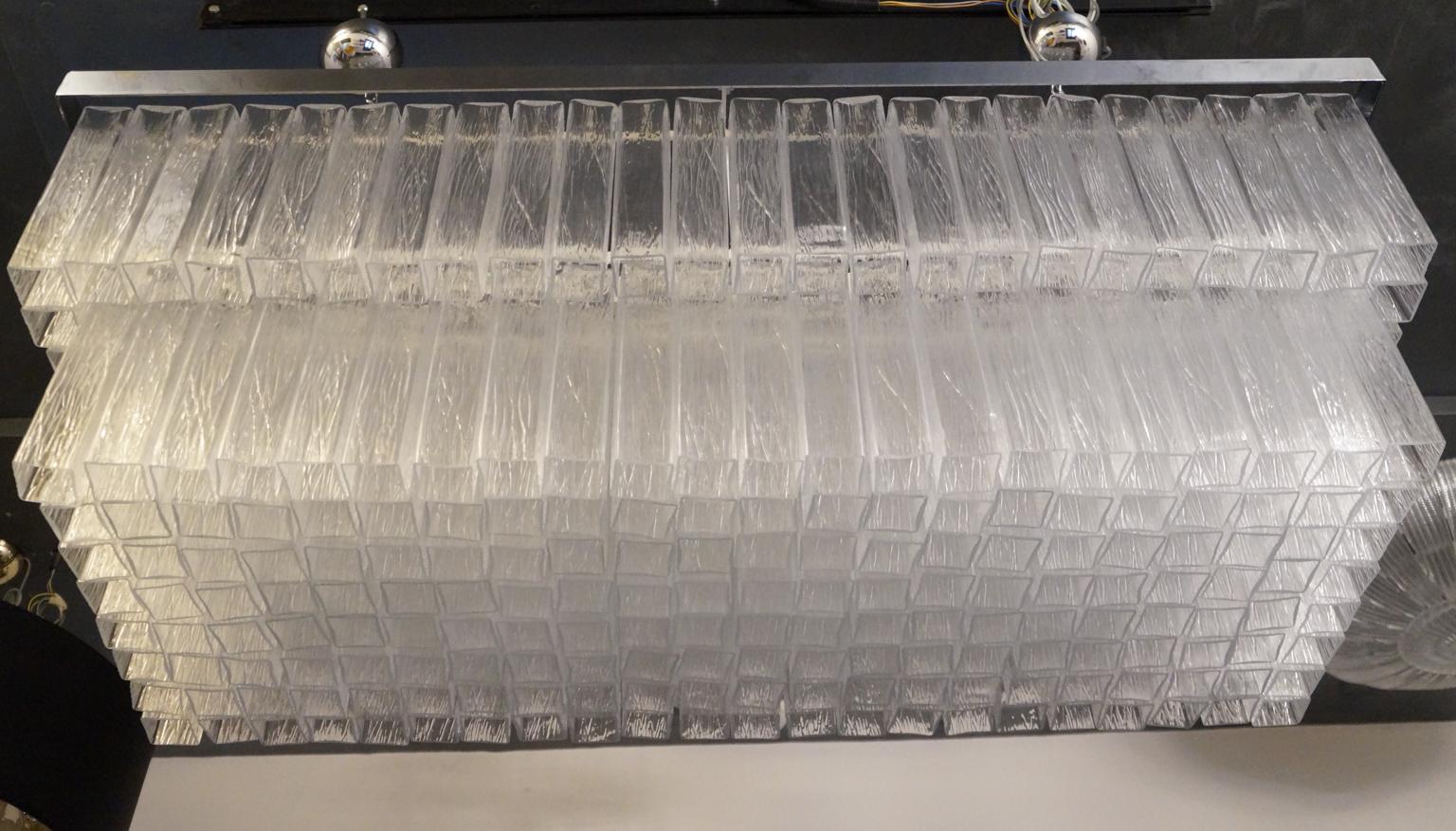Fantastico lampadario in vetro soffiato di Murano con 240 elementi a forma di tubo quadrato color cristallo.
I tubi di vetro hanno una lavorazione chiamata 