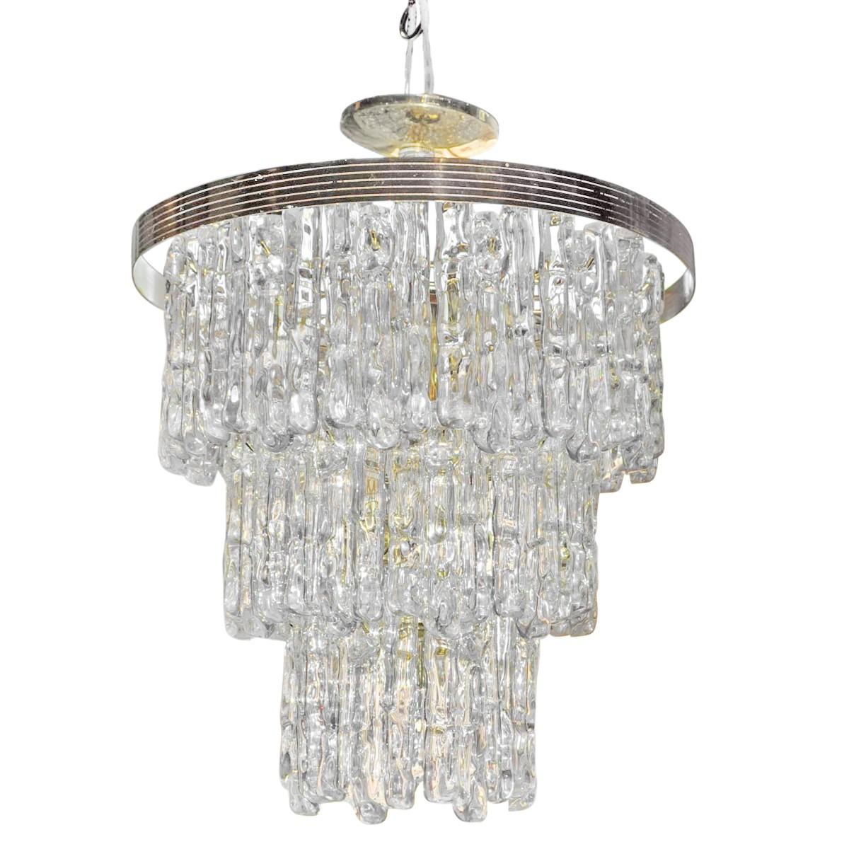 Italian Hollywood Regency style modern three-tiered waterfall chandelier with gold brass frame and ice-like Lucite/acrylic prisms. Original wiring in working condition. Eight candle base bulbs. 40 watts each. Brass-plated canopy included. 

In the