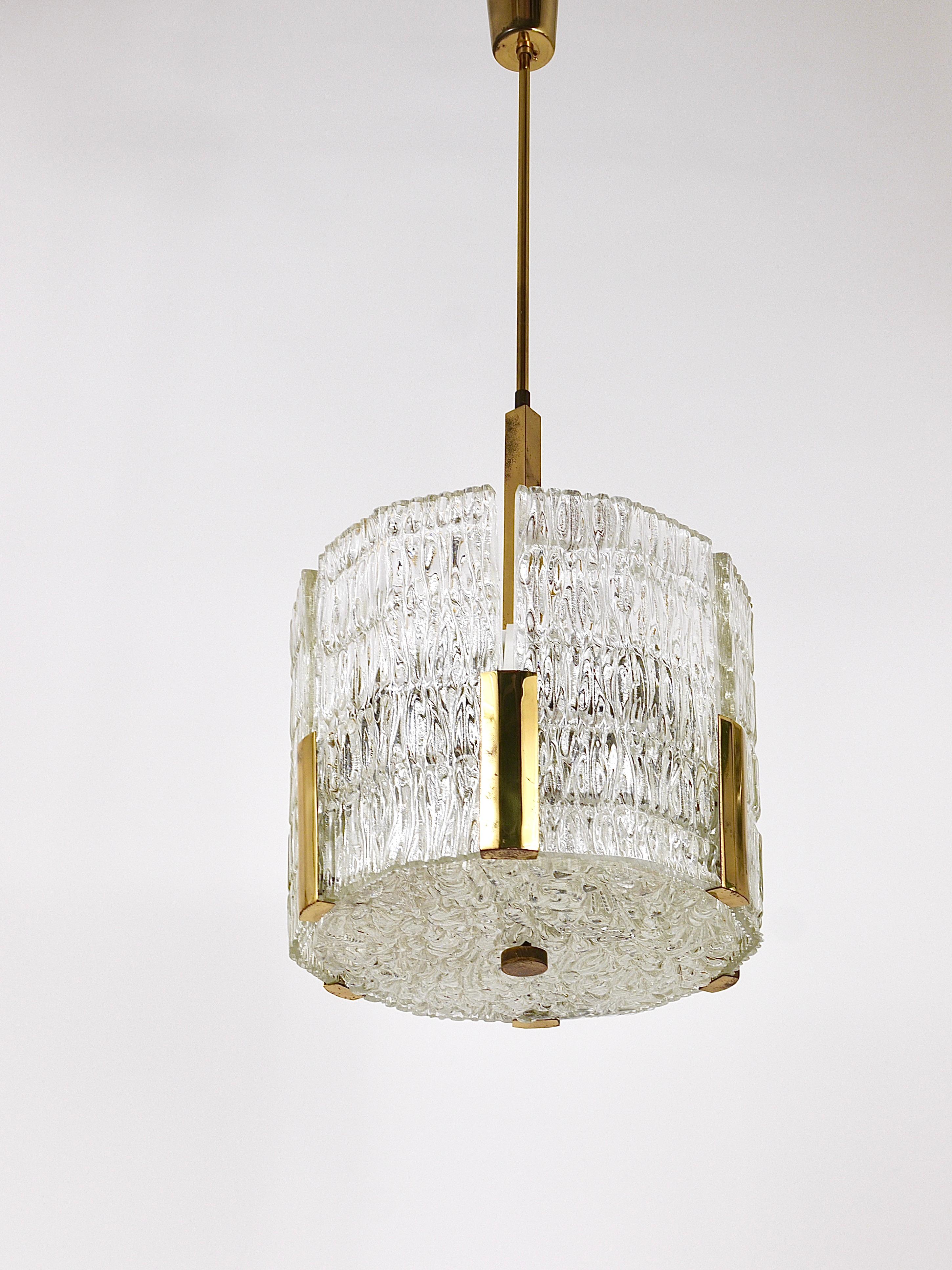 A beautiful midcentury brass drum chandelier from the 1960s, executed by J.T. Kalmar, Vienna/Austria. Consists of a metal frame with six solid textured melting glass panels, a dodecagonal glass plate on its bottom. On a brass rod with nice brass