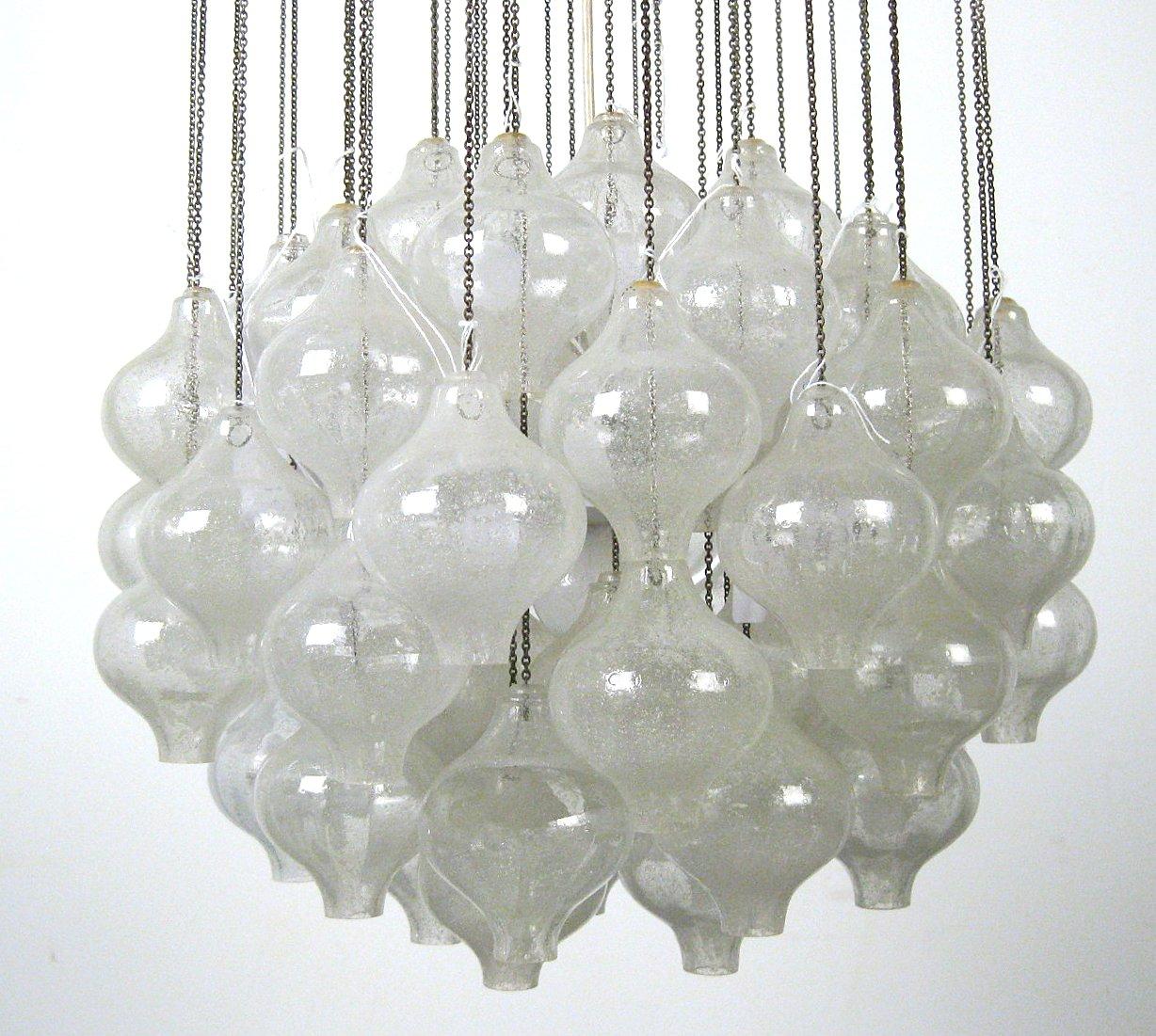 Large Kalmar chandelier that consist of numerous blown glass elements which are highly saturated with tiny air bubbles that gives the glass a white look, each element is resting on a nickel chain hanging from a wood ceiling plate, elements are